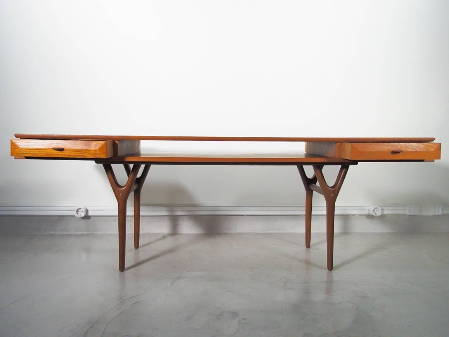 Rectangular teak coffee or console table with four drawers and a storage compartment in the center. Slender V-shaped legs. Produced in Denmark in the style of Johannes Andersen.
