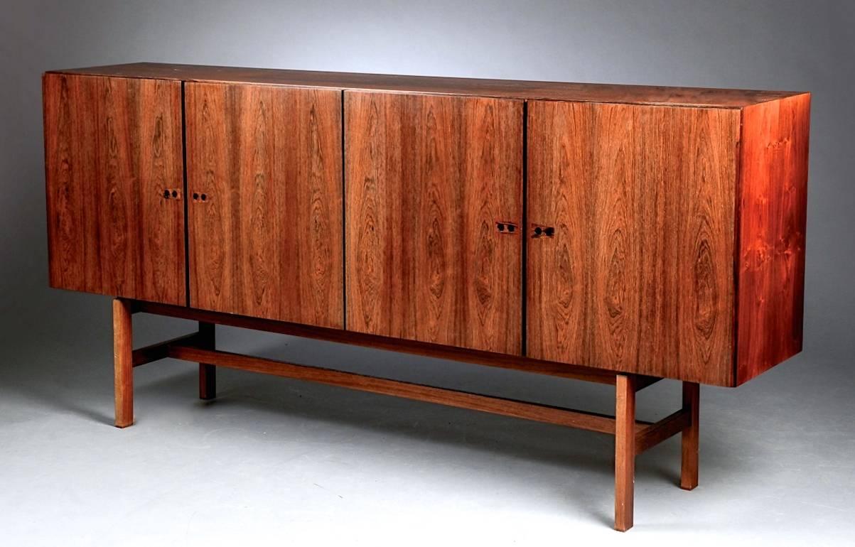 Large Danish rosewood credenza designed by Ib Kofod-Larsen. Built-in lighting and interior mirror. Adjustable shelves, three felt-lined pull-out trays and two drawers. Manufactured by Faarup Møbelfabrik in Denmark.