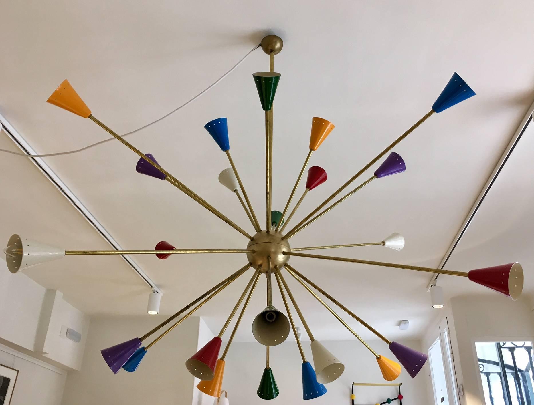 Large sputnik pendant lamp in the style of Stilnovo. Rods of brass, fitted with 24 lighting outlets with cone-shaped reflectors of sheet metal varnished in several colors. The central sphere is varnished in gold color. Minor wear, the varnish of the