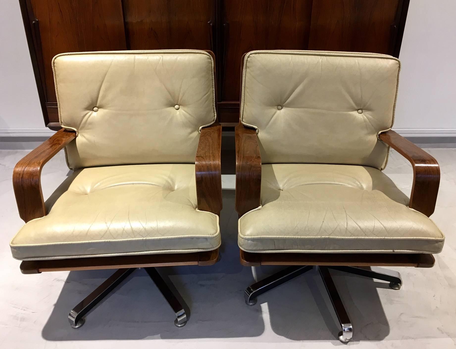Pair of handmade cream-colored leather swivel armchairs with a steel base and solid rosewood frame. Button tufted upholstery. Made by AG Barcelona in Spain during the 1980s.
