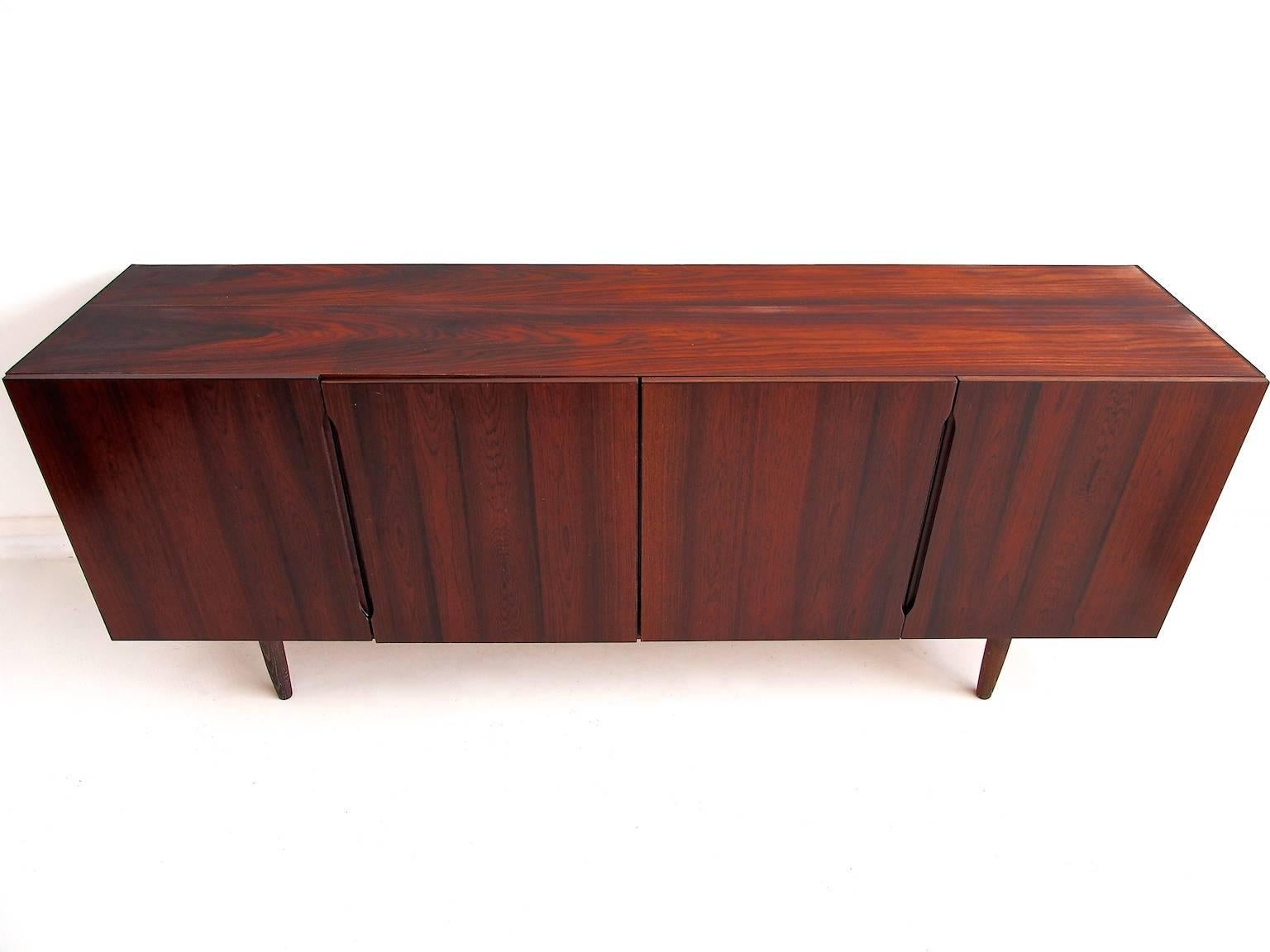 Low sideboard in rosewood manufactured by Bramin Møbler in Denmark, circa 1960s. Front Four doors enclosing drawers and shelves. Later mounted tapered legs.