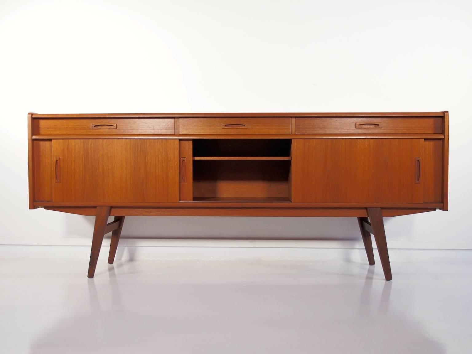 Danish modern sideboard veneered with teak from circa 1950s. Front with three drawers and three sliding doors behind which are shelves.