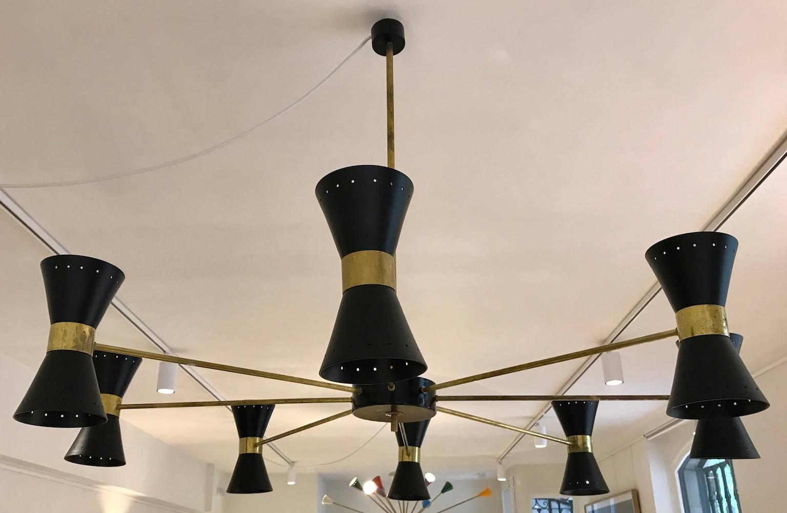 Large hanging lamp in the style of Stilnovo. Sixteen lamps, cone-shaped reflectors, painted black metal, featuring two lamps each, brass rods. Minor scratches and age-related wear on brass.