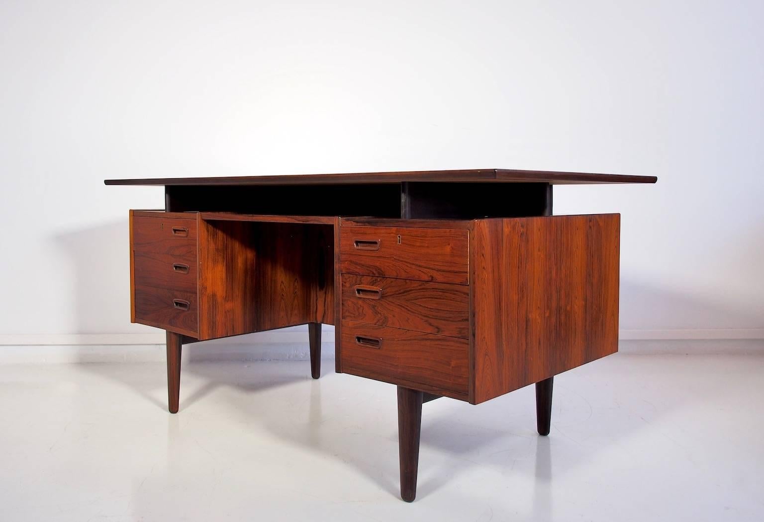 Danish rosewood writing desk, recently restored. Equipped with two containers with three drawers on each side. Backside pocket with flap and bookshelves. Excellent condition.