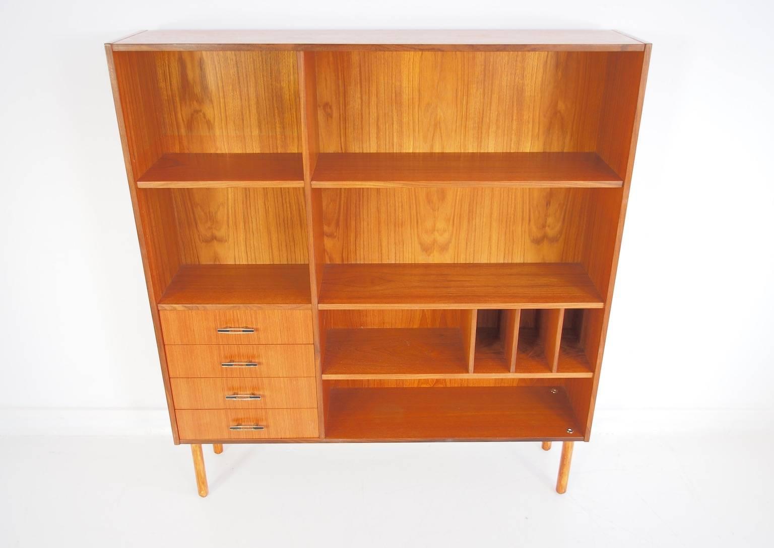 Scandinavian Modern teak bookshelf or shelving unit with four drawers, shelves and smaller storage compartments. Legs made of pine.