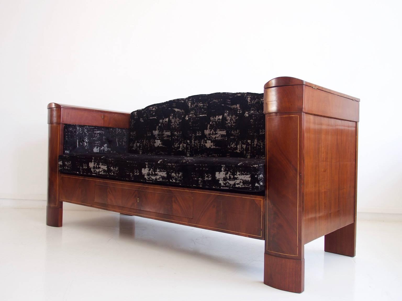 Mahogany cabinet sofa / daybed from the Danish Empire period, circa 1820s, with inlaid strips of light wood. The armrests have lockable compartments and there is a drawer under the seat. Keys included. Restored and reupholstered with patterned black