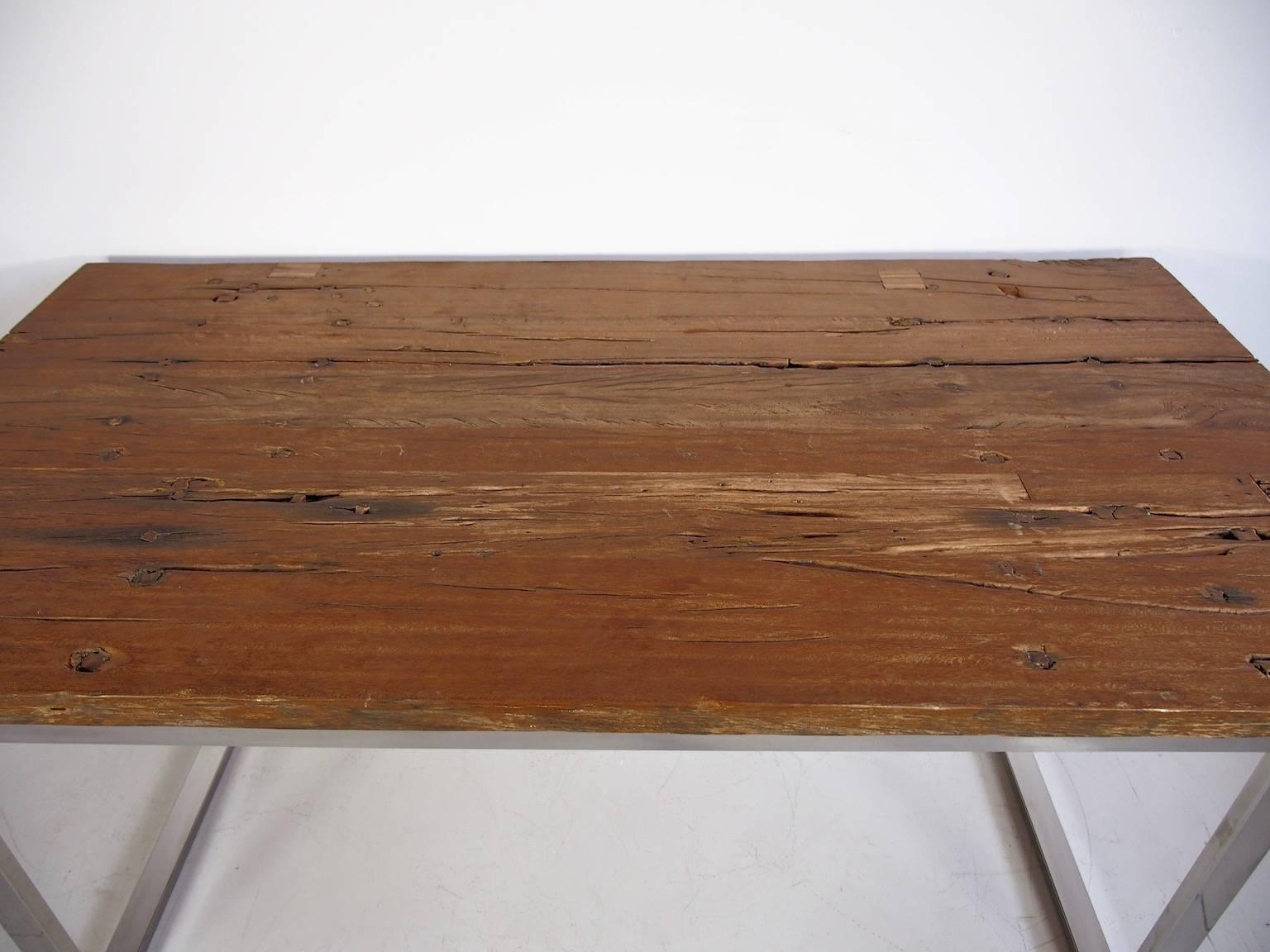 Ancient bridge wood dining table. Salvaged wood over chromed metal base. 
The bridge series uses materials salvaged from old Indonesian bridge.
Signs of wear, some drying cracks on tabletop.