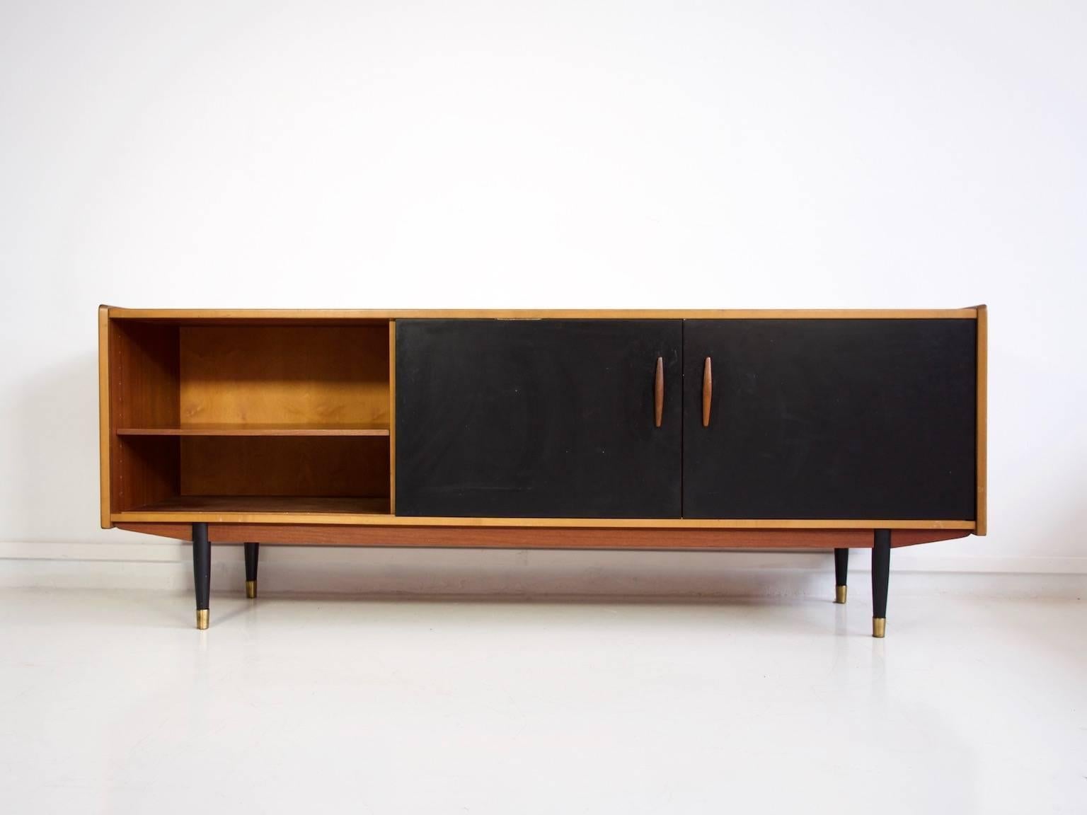 Teak sideboard by H. Troeds with five drawers in the middle and black laminate covered sliding doors on the sides, behind which are drawers. Feet with brass shoes, circa 1960s.