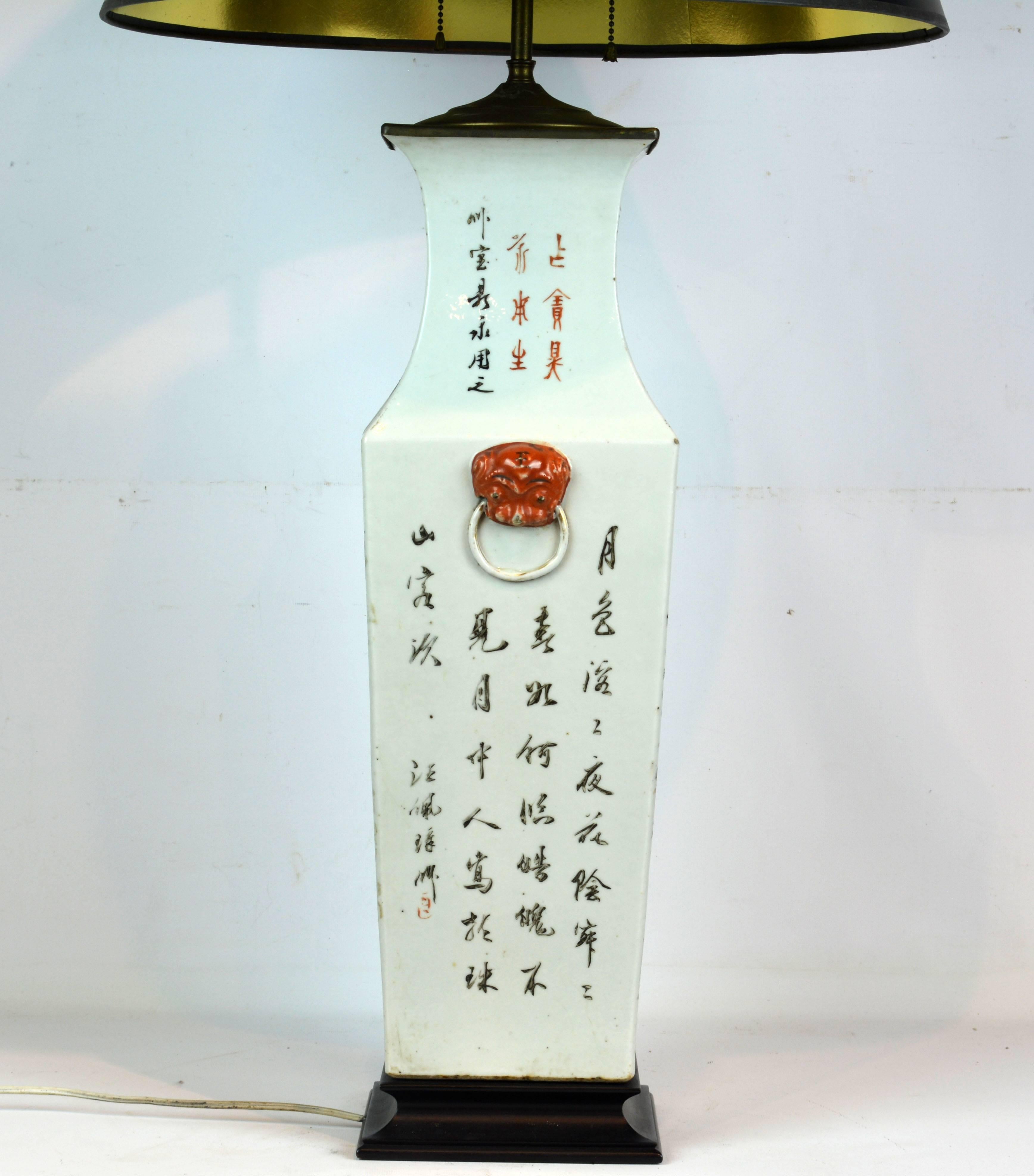 Of generous proportions this antique vase lamp of the Famille Rose style features lively motifs with people, children and blossoming trees on the two opposing sides and Chinese inscriptions in red and black accented by red foo dog masks on the two