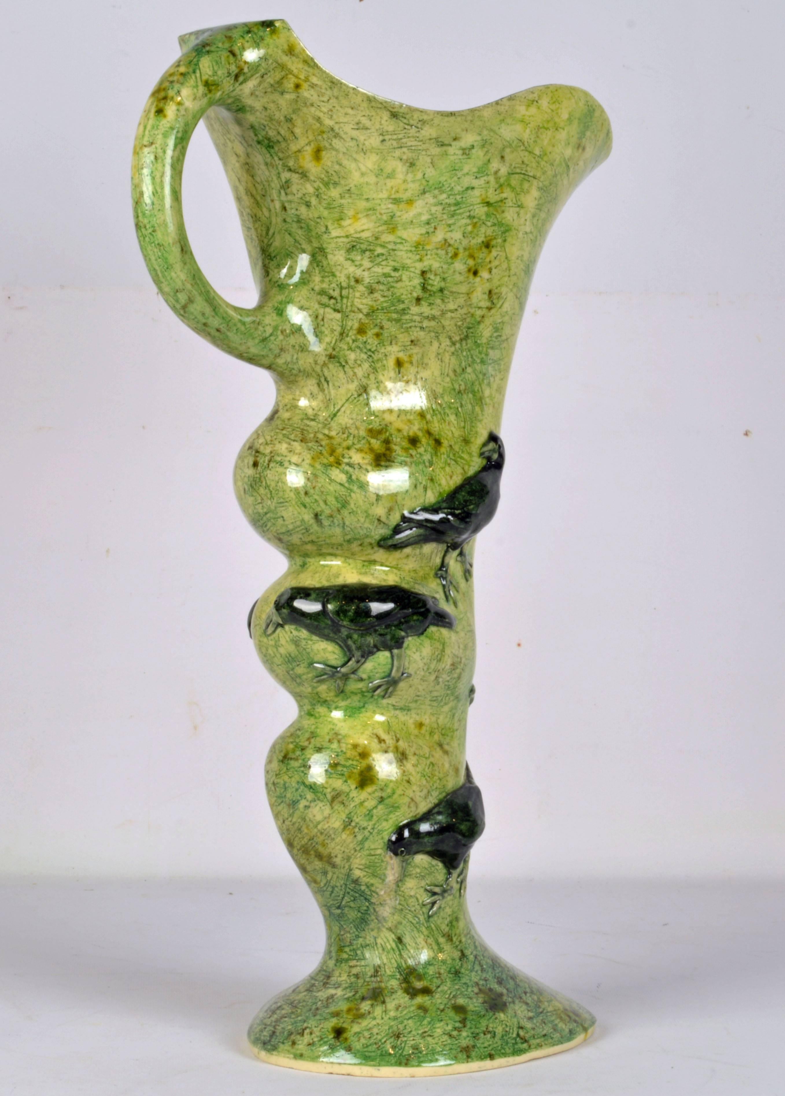 Standing 28 inches high and signed by the artist this sculptural vase with green glaze and raised bird reliefs features rich connotations of nature, sustainability and organic references, its unique design offering an ever-changing form from every