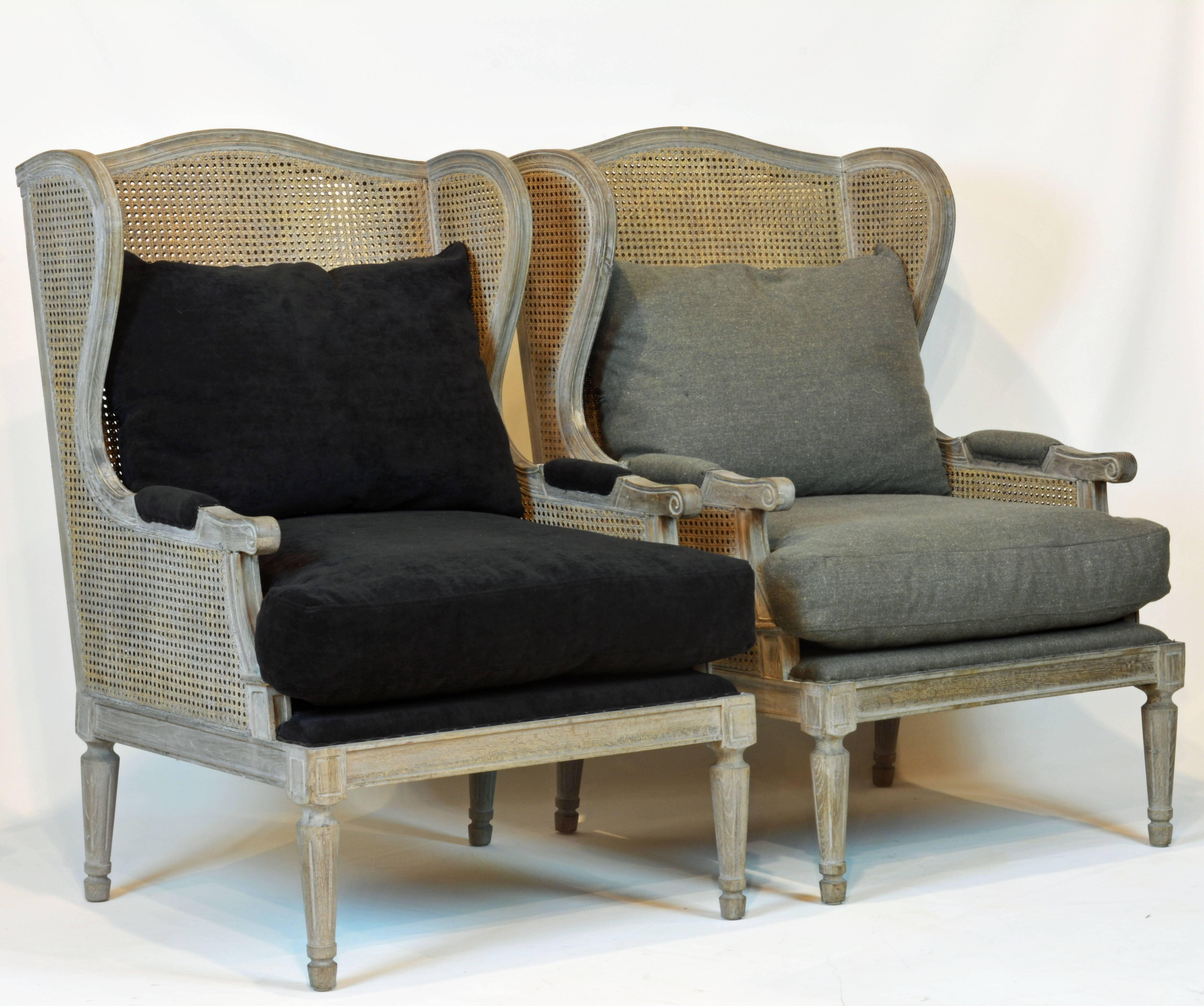 Cushioned one in black and the other in grey fabric, these chairs finished in a Puritan grey make an inviting and individualized impression. Wide and comfortable the construction features double cane walls and simplified Louis XVI design details