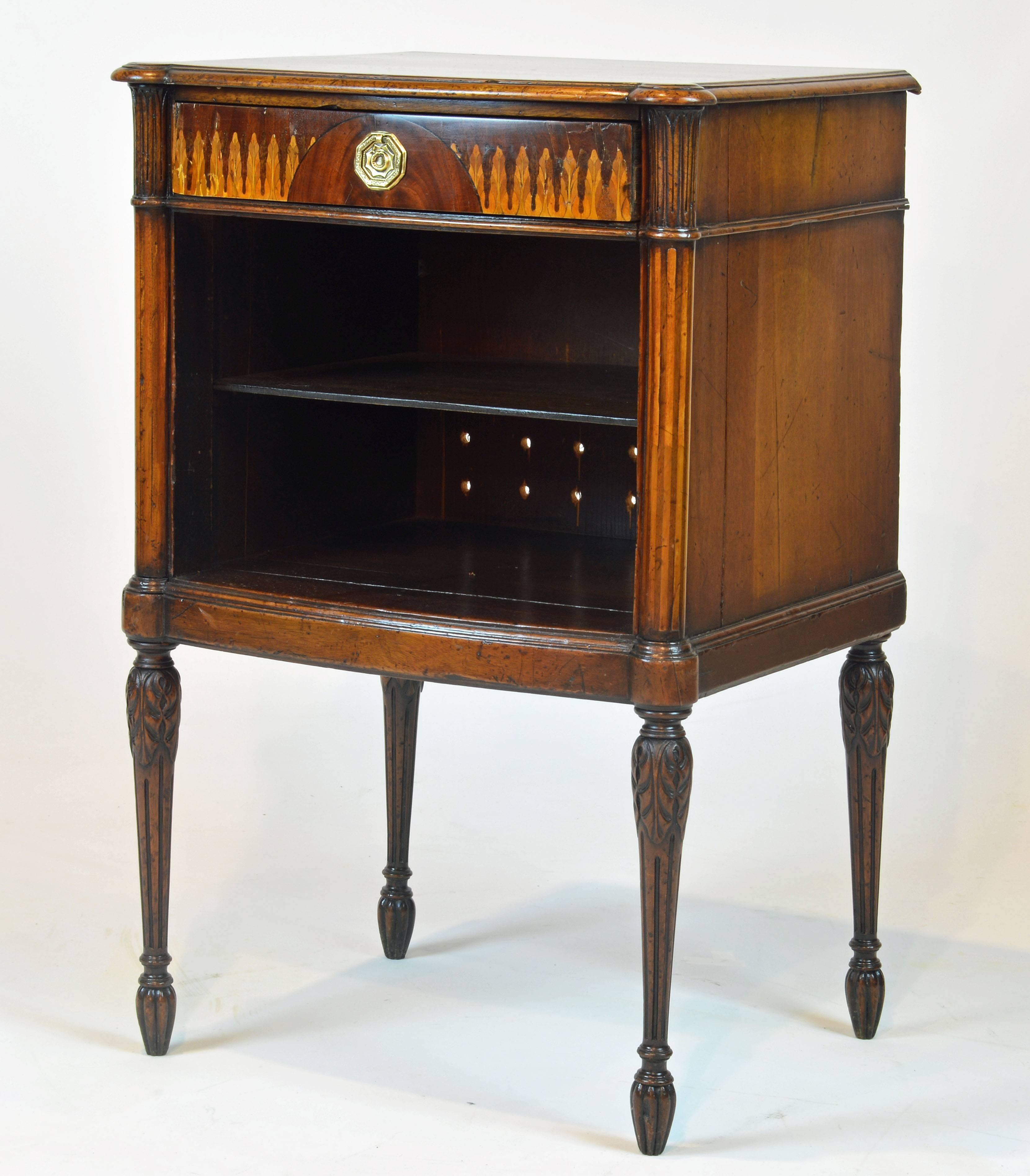 This delicate bookstand features a mahogany top with moulded edges and ears corresponding to the front legs above a single drawer centering a circular classical arch flanked by Art Nouveau inspired leaf inlay. Under the drawer a one shelf open