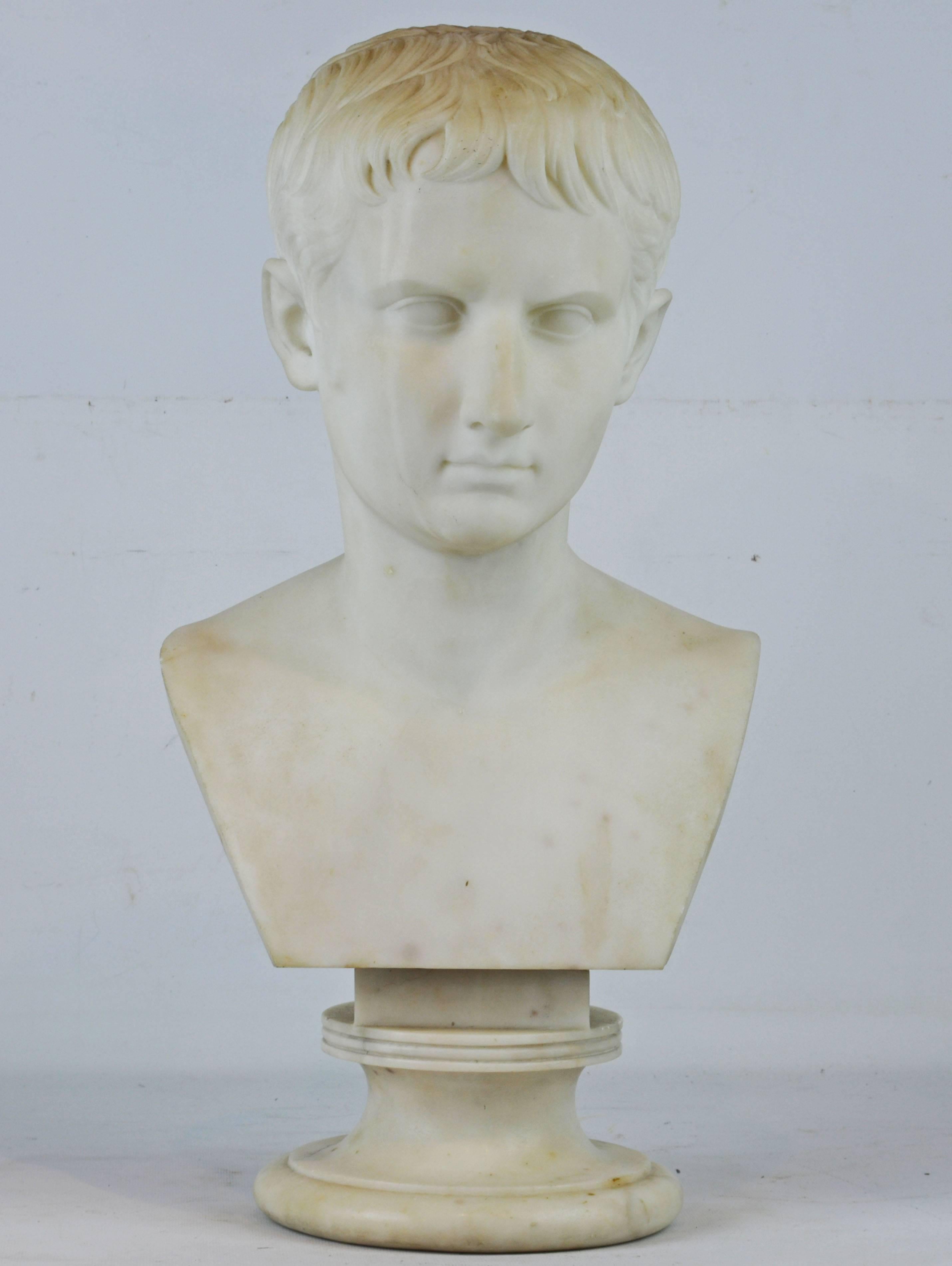 Standing 22 inches tall the white Carrara marble bust of the Young Octavian rests on a waisted circular base and is of Italian origin carved after the antique' Young Octavian' end of 1st century BC, now in the Vatican Museums - Pius Clementinus