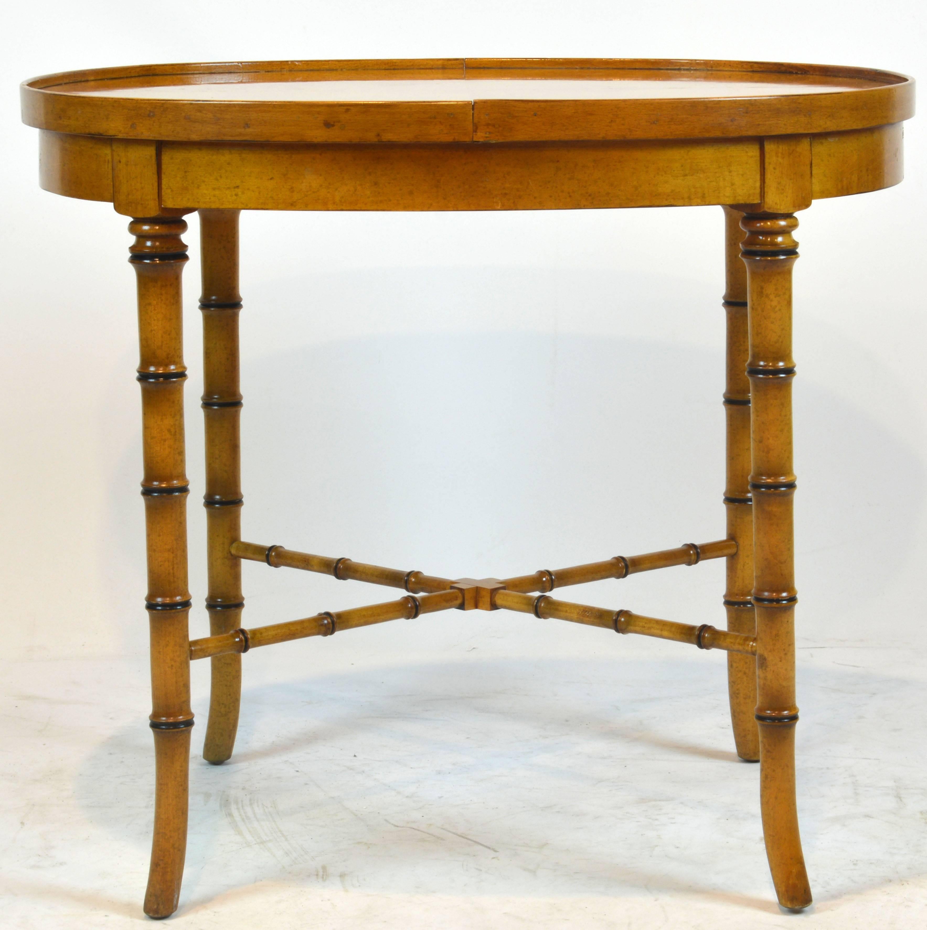 This good looking table in the Regency style features a honey colored polished maple tray like top and underlying frieze above four bamboo carved splayed legs united by a traditional X-stretcher.