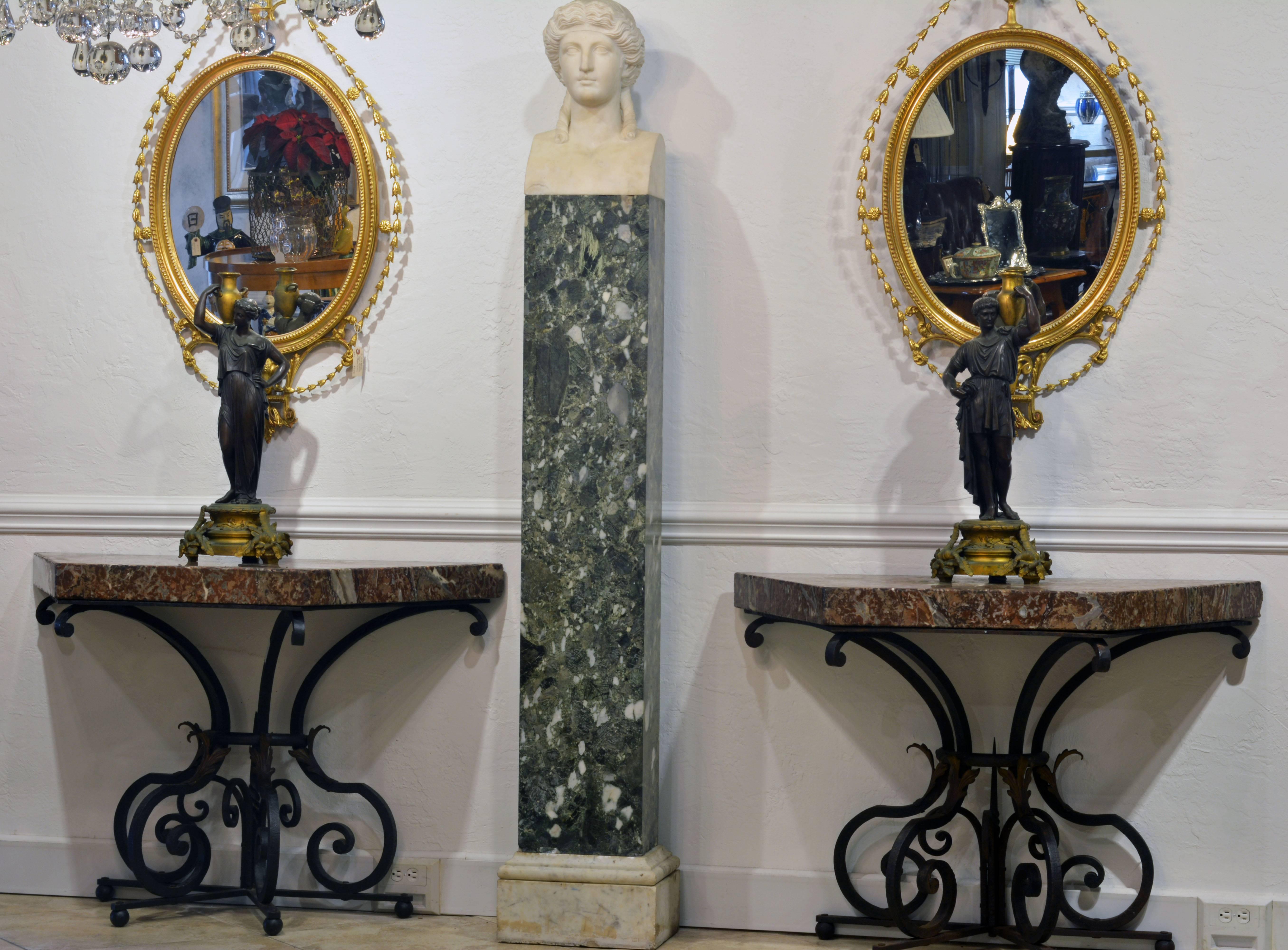 The thick marble rouge des Pyrenees tops surmounting intricately scrolled ebonized wrought iron bases accented by gilt tole leaf-work and terminating in a set of four iron ball feet. The style is reminiscent of the Mizner interpretation of