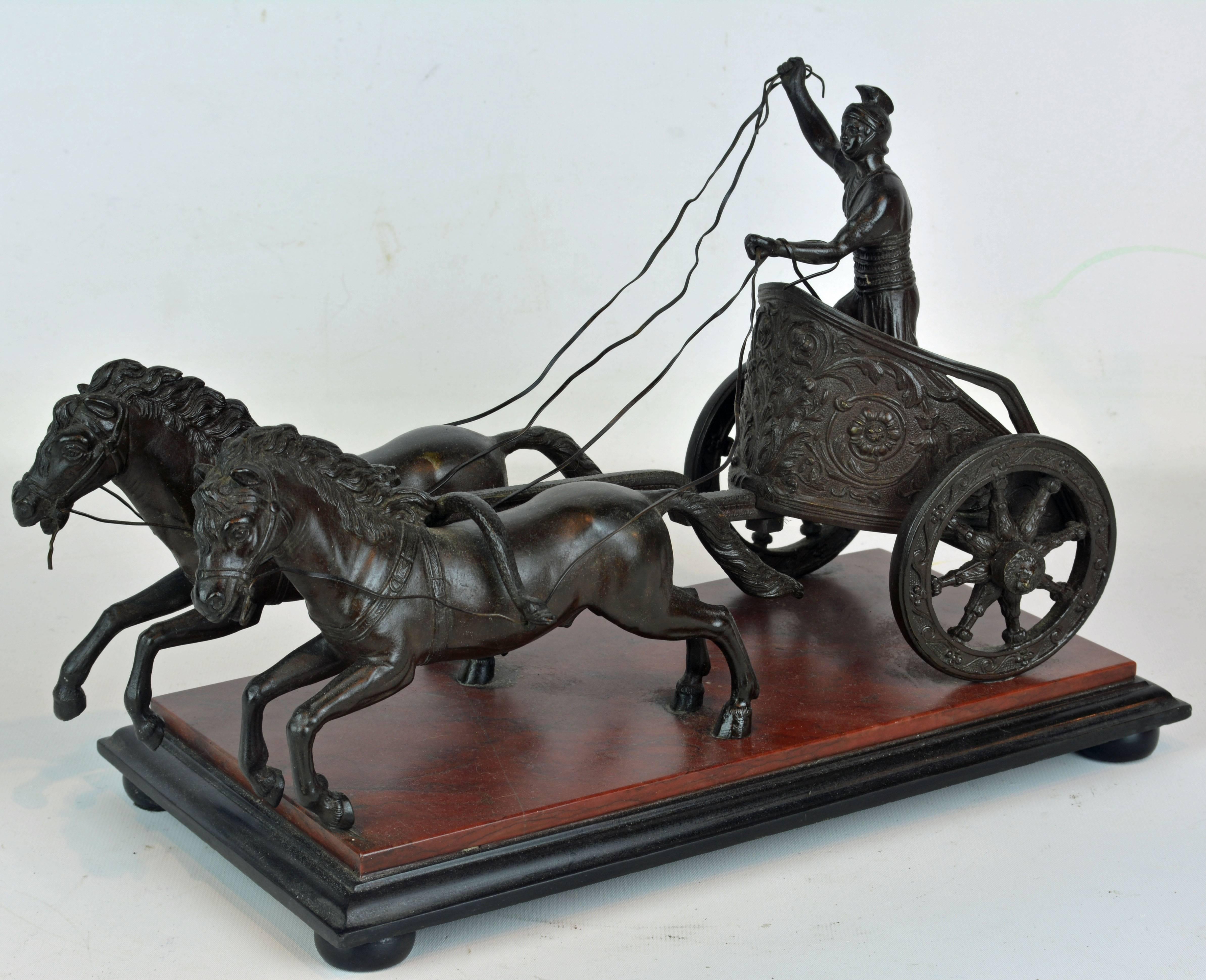 A late 19th century Italian grand tour bronze group representing a Roman charioteer standing in his 'biga' chariot drawn by two horses. The bronze features great detail in as well the surfaces of the chariot as the flowing reins and is mounted on a