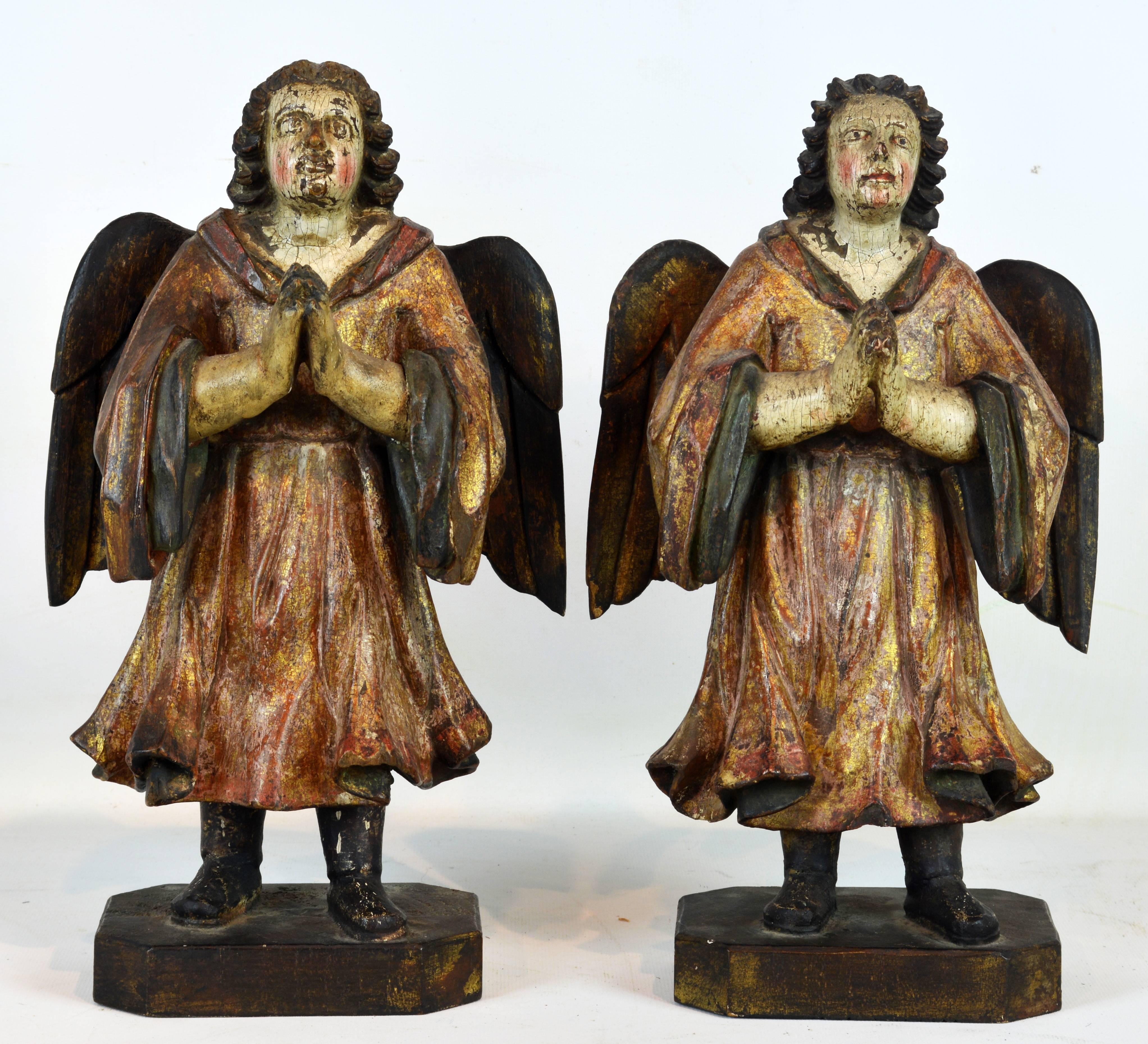 The early 19th century angels standing 13 inches tall with individualized facial expressions resting on square wooden bases with hands folded in prayer wearing beautifully carved robes.