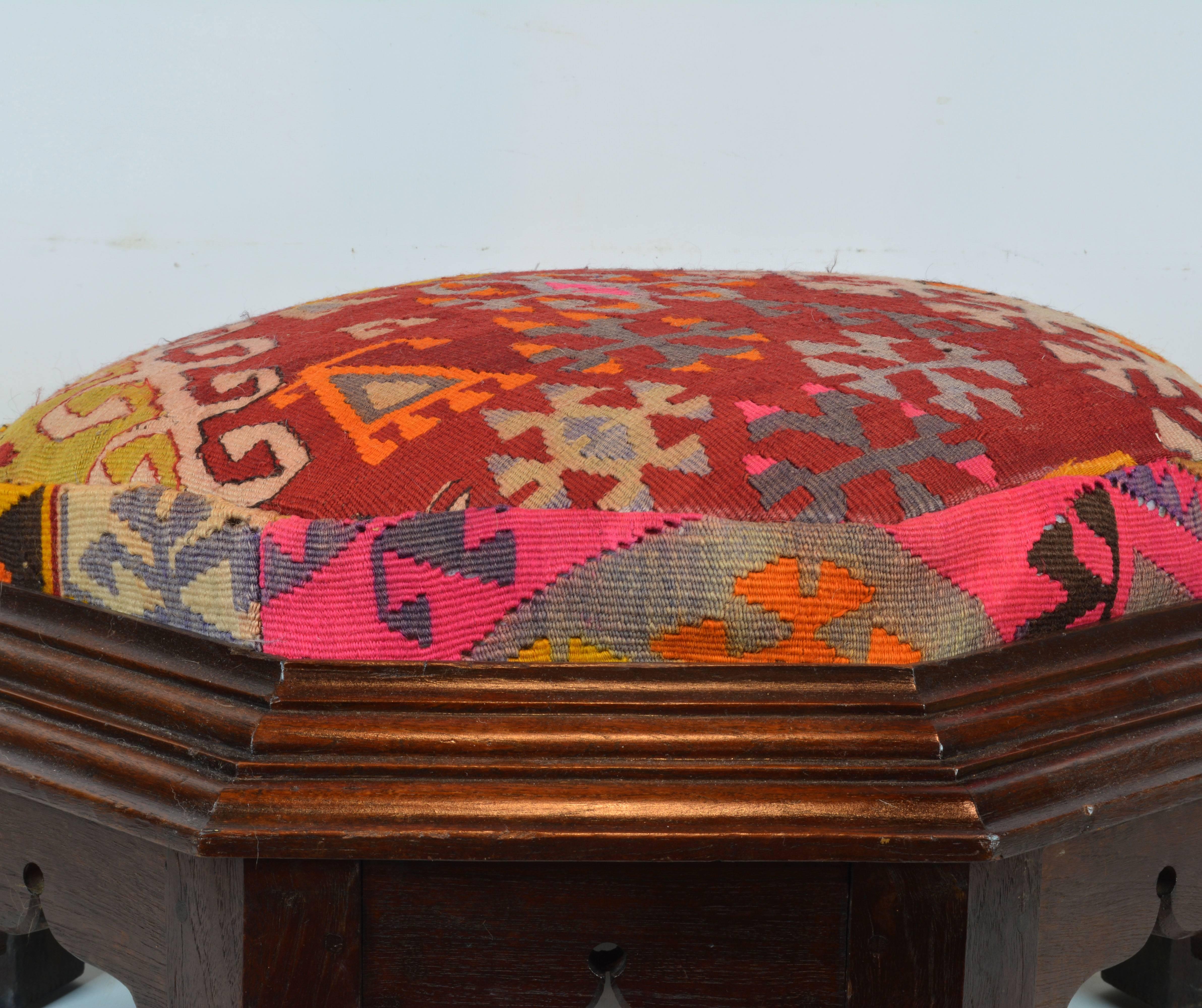 Standing on eight legs flanking carved oriental openings this ottoman features a richly moulded frame surrounding the upholstered seat covered with colorful geometrical pattern Kilim rug.