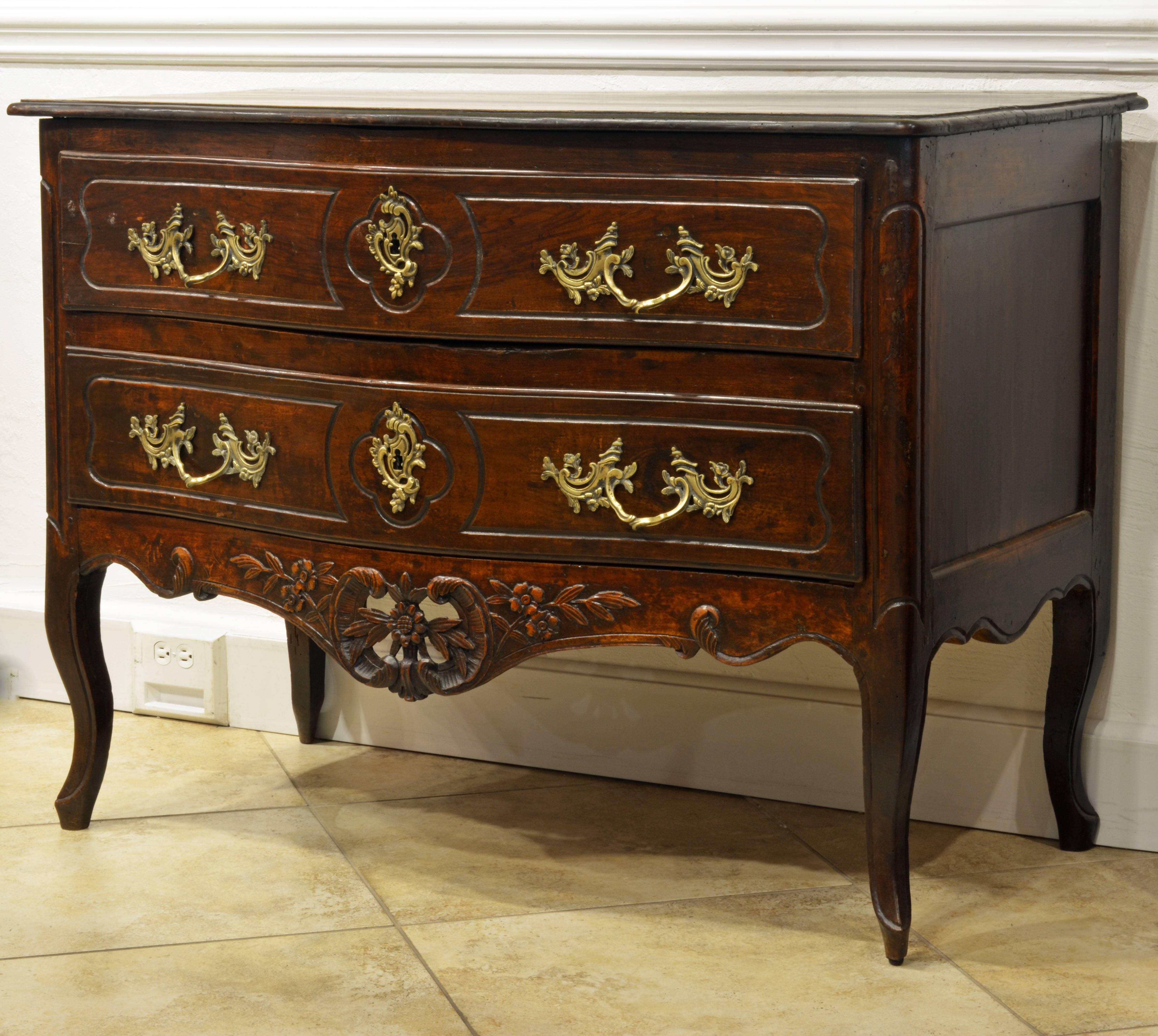 This charming commode features the Italian romantic version of the Louis XV style that was blooming in France at the time. The two delicately profiled serpentine drawers, mounted with typical Rococo gilt bronze hardware, above an open work carved