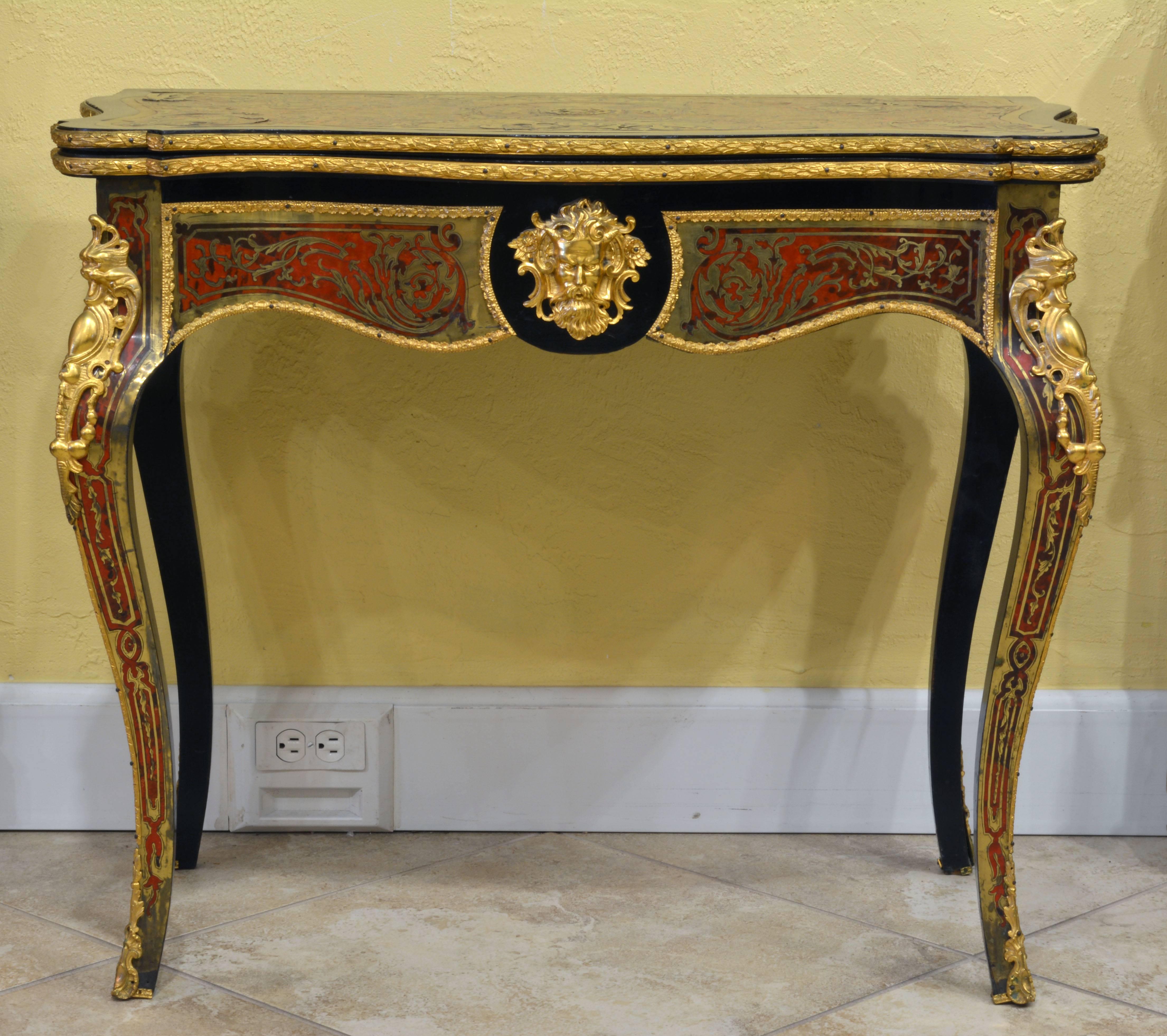 A refined Boulle table from the mid-1800s. The surface consists of Dyed tortoise shell inlay combined with bronze doré arabesques and lacquer finish. The top rotates to create a game table. The felt lined elegantly shaped top with borders of boulle