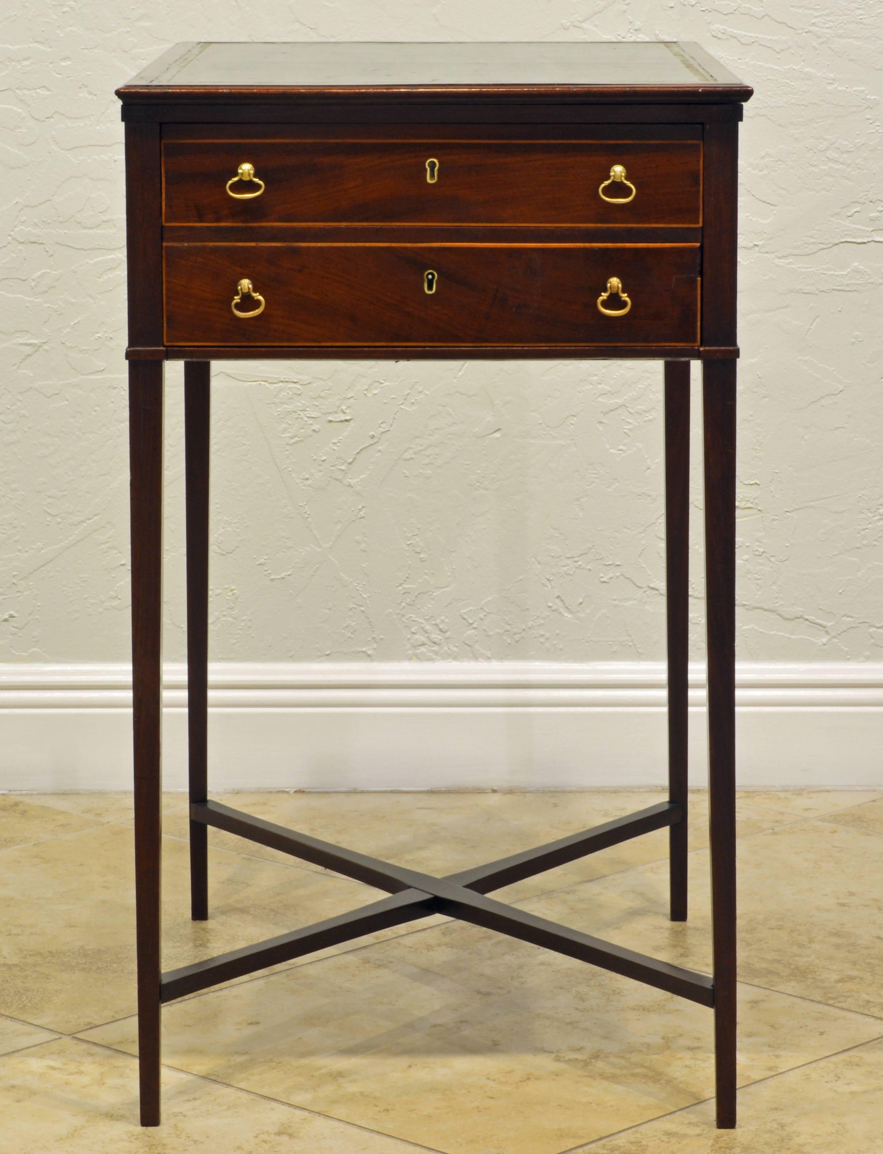 This interesting and unusual table features an adjustable sloping banded and gilt tooled green leather writing surface above two drawers on either side, one with inserts for writing tools, resting on square tapering legs united by crossed