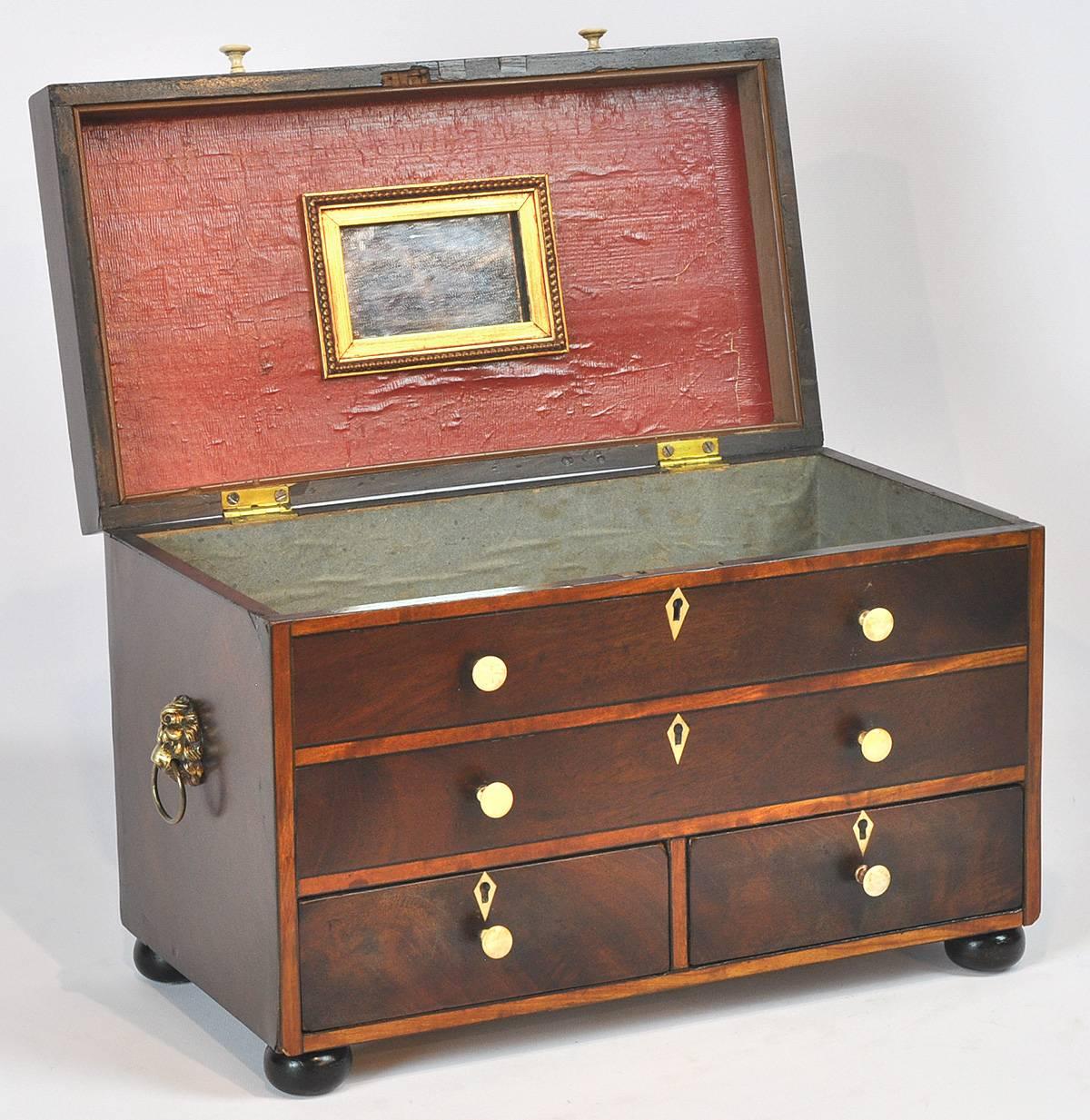 Two-drawer mahogany jewel box with banded satinwood fronts, lion handles, circa 1820s.