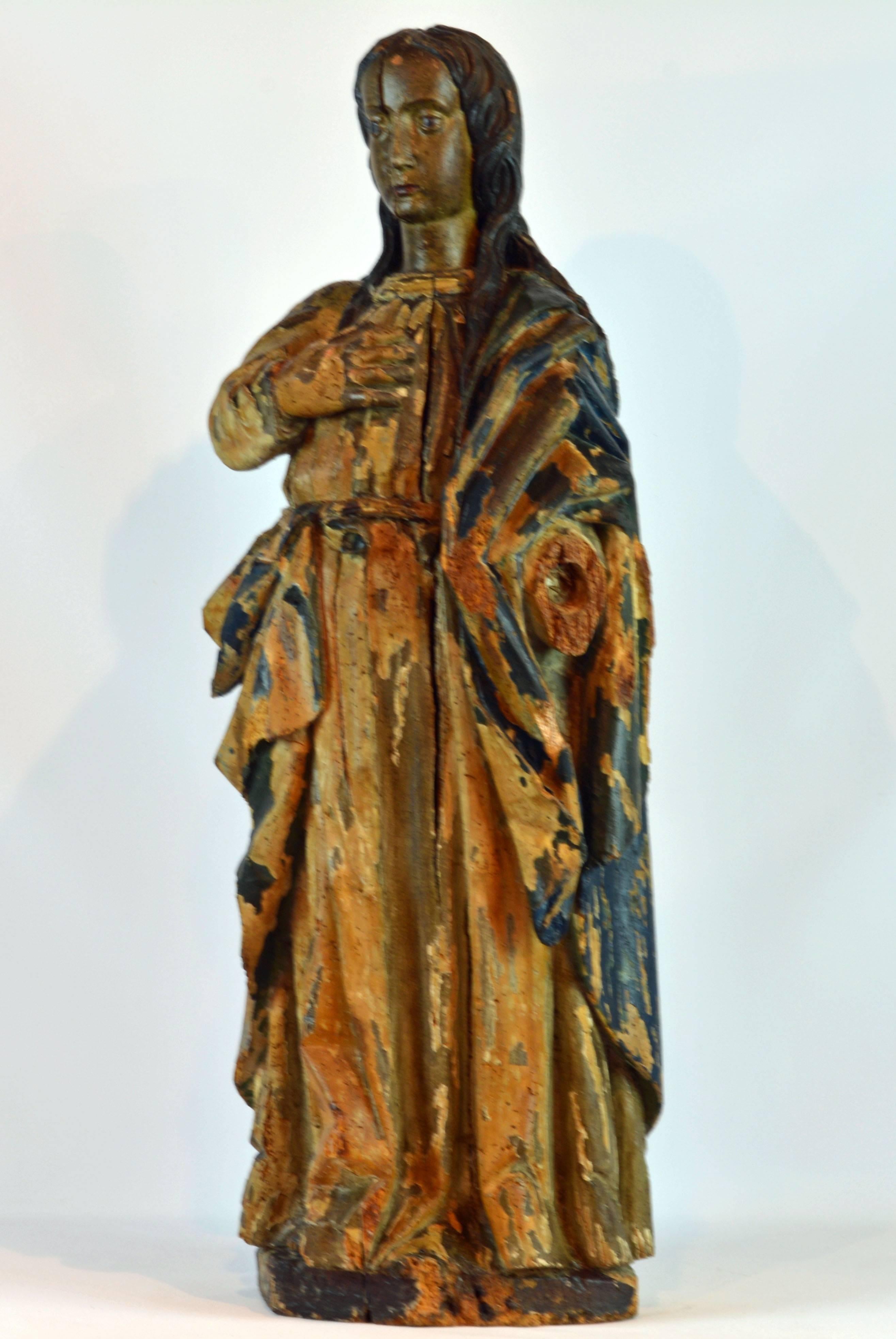 Standing 39 inches tall this statue of the Penitent Mary Magdalene features the saint standing wearing pleaded gown and draped mantel with her right hand to the heart and with her elaborately carved long hair down over her shoulders. The statue