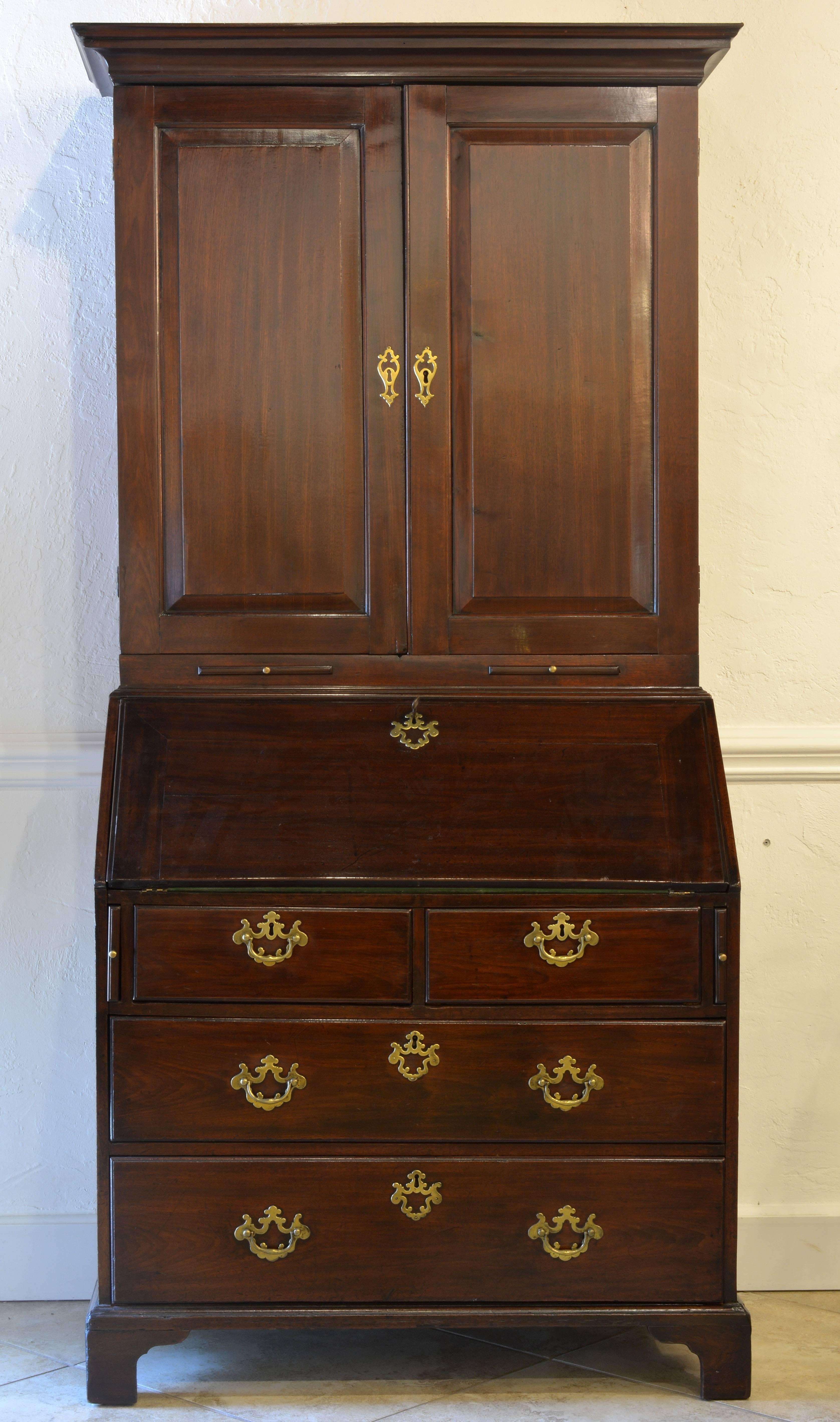 A charming secretary bookcase of rather small proportions. The upper part with two doors opening up to a shelved interior, the lower fall front desk fitted with small compartments and drawers with original brasses above two short and two long