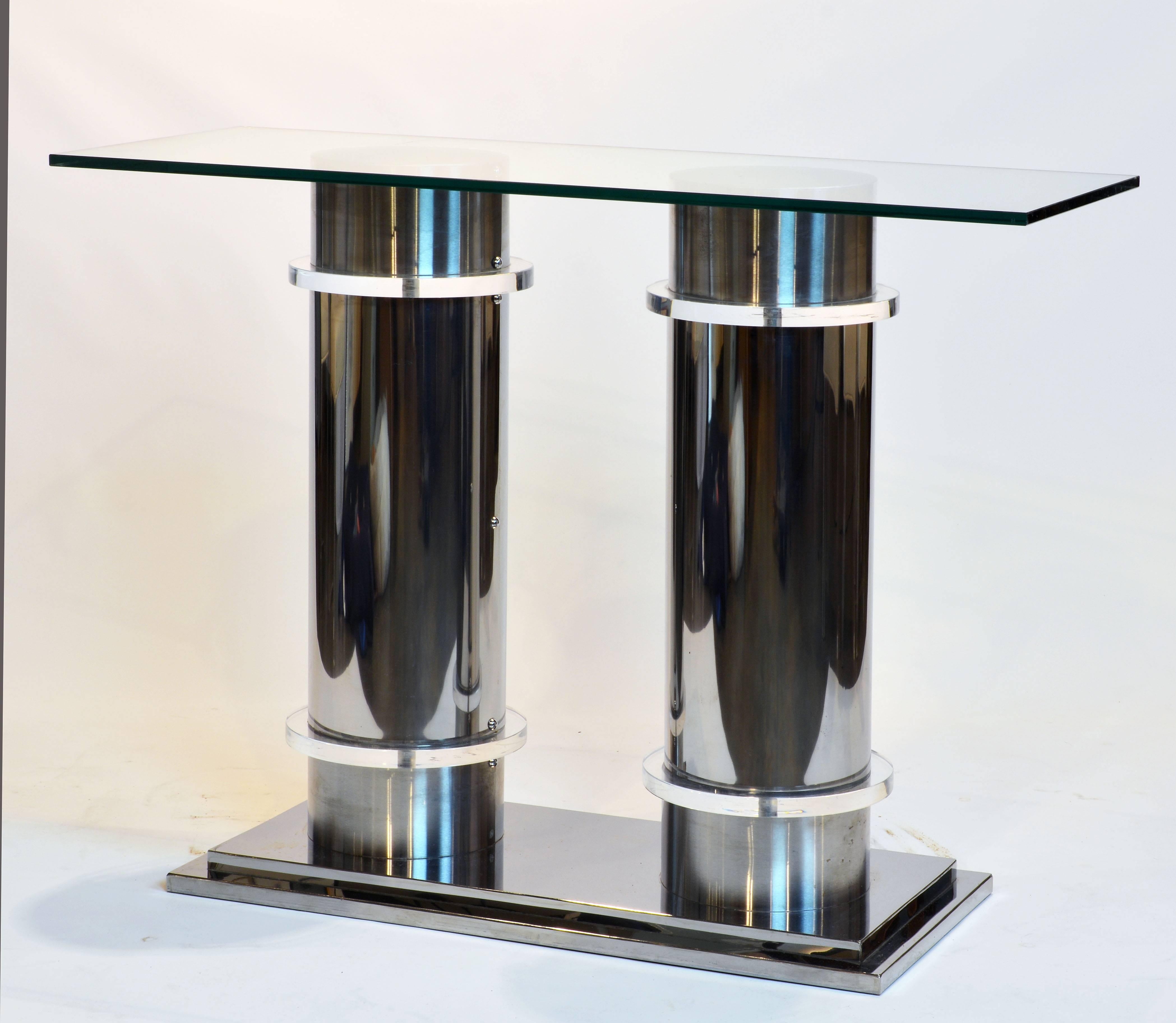 The glass top resting on two columns standing on a stepped chrome base. The columns combine brushed aluminium tops and bottoms centring the chrome midsection divided by thick Lucite disks. A sharp almost neoclassical design.