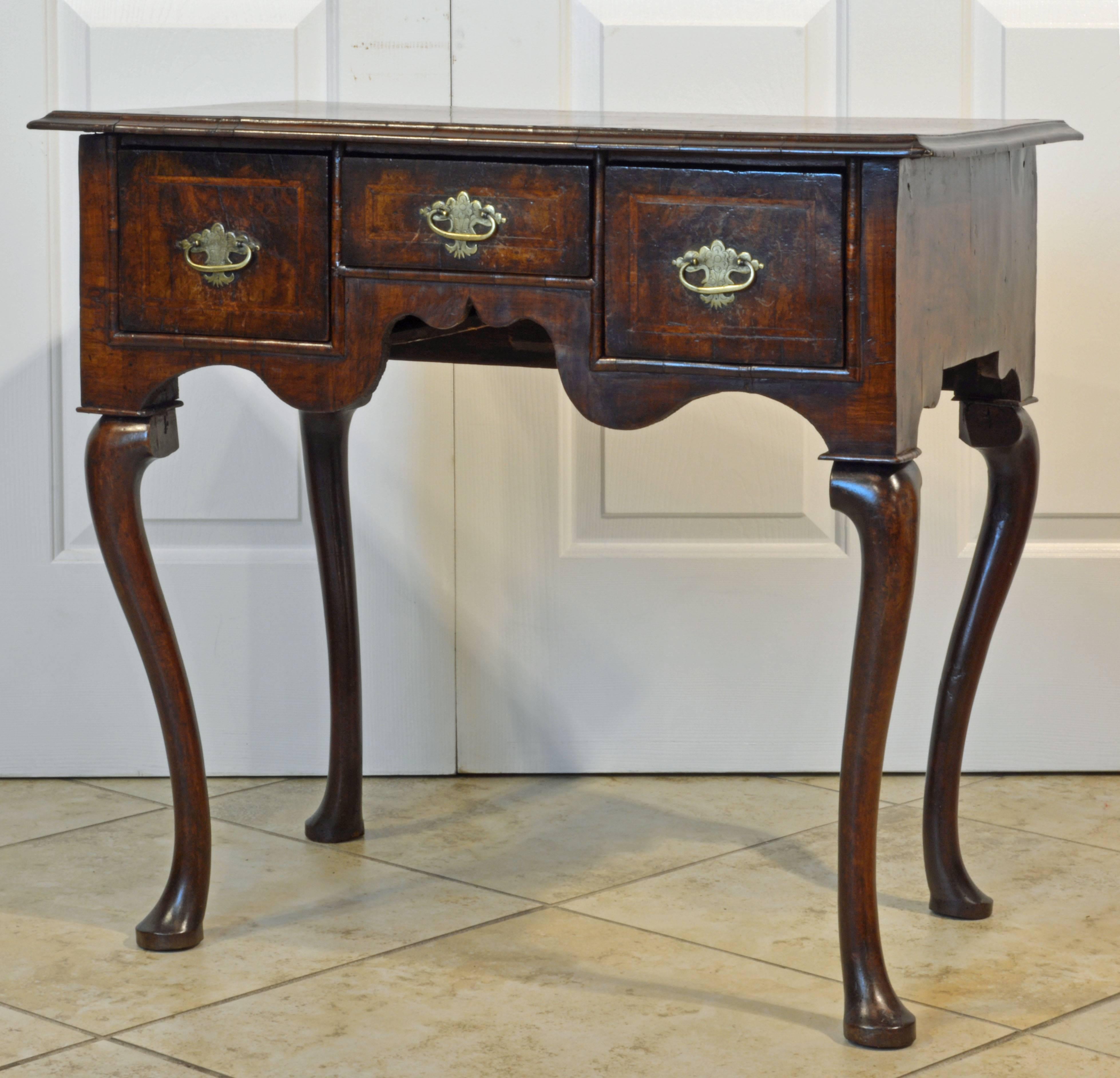 This fine 18th century dressing table or low boy features a cross banded and herring bone stringed top above three similarly banded drawers and a shaped apron resting on four cabriole legs ending in pad feet.