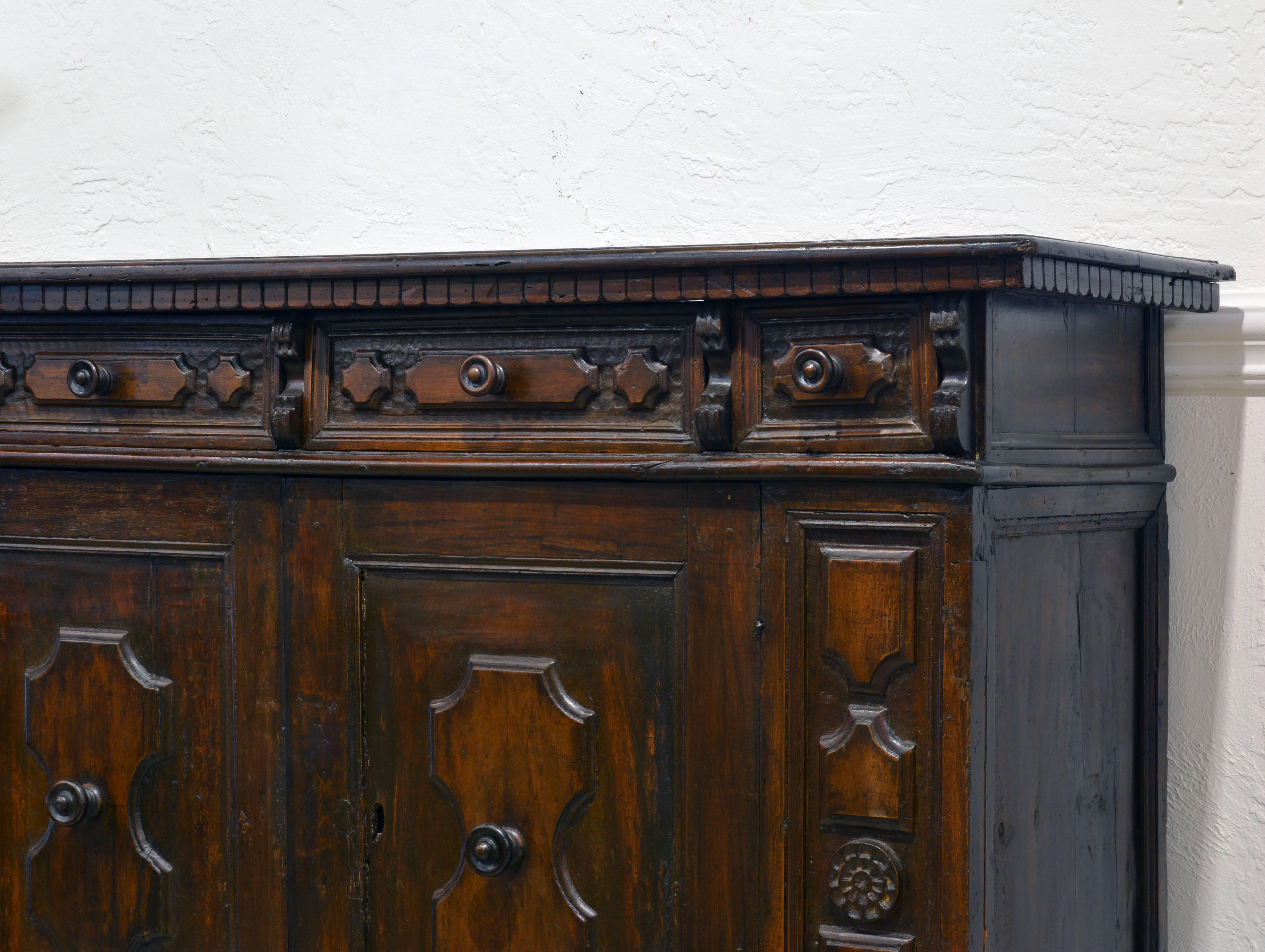 This carved buffet is a fine example of Italian Provincial Baroque featuring a one plank top of beautiful patina above four carved frieze drawers and two doors flanked by carved panels.