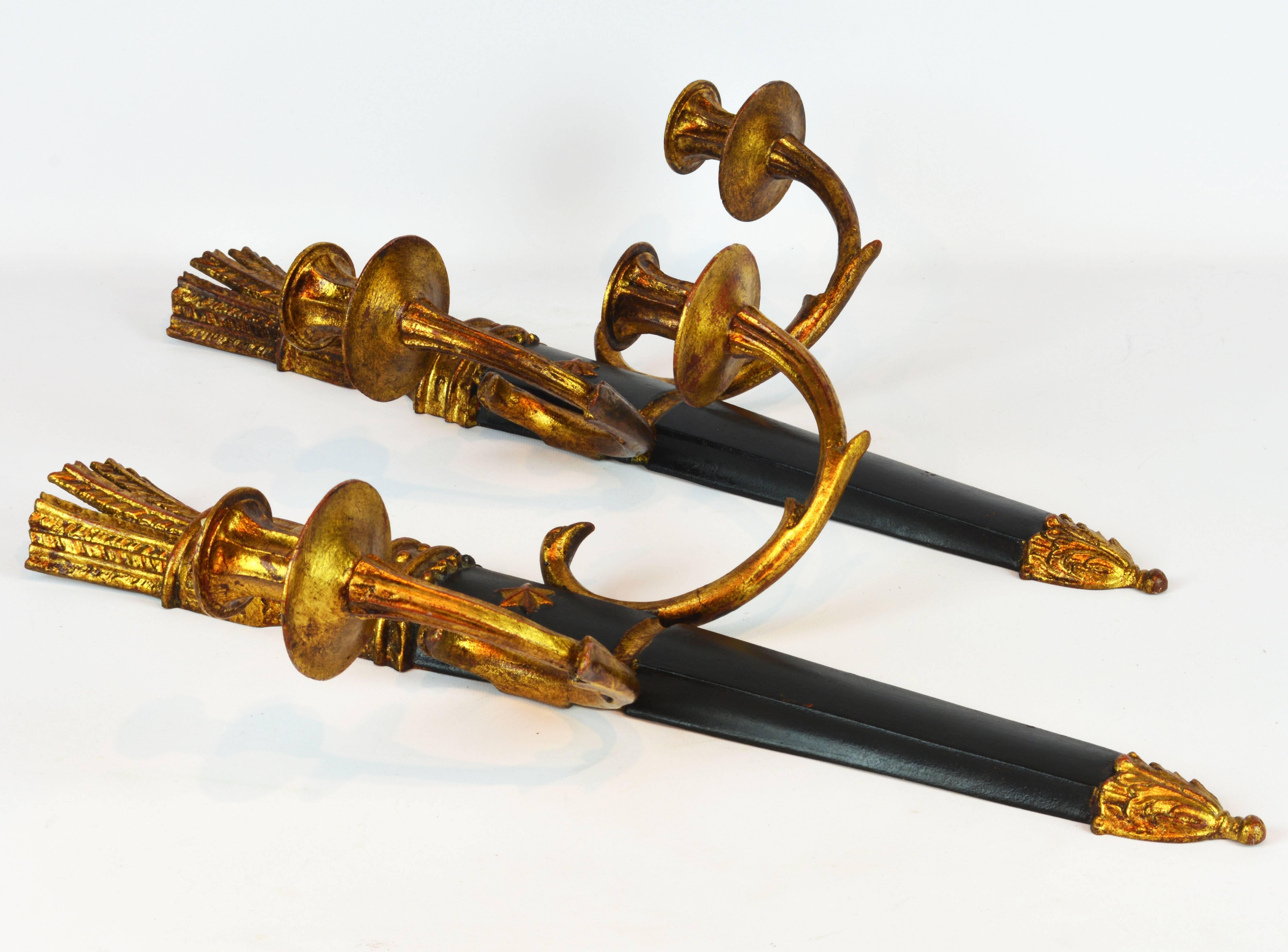 These elegant wall sconces feature a center ebonized and parcel-gilt stem surmounted by arrow heads supporting two gilt metal candle arms adorned with scrolled leaf work in the style of Louis XVI. On the back old Palladio labels.
