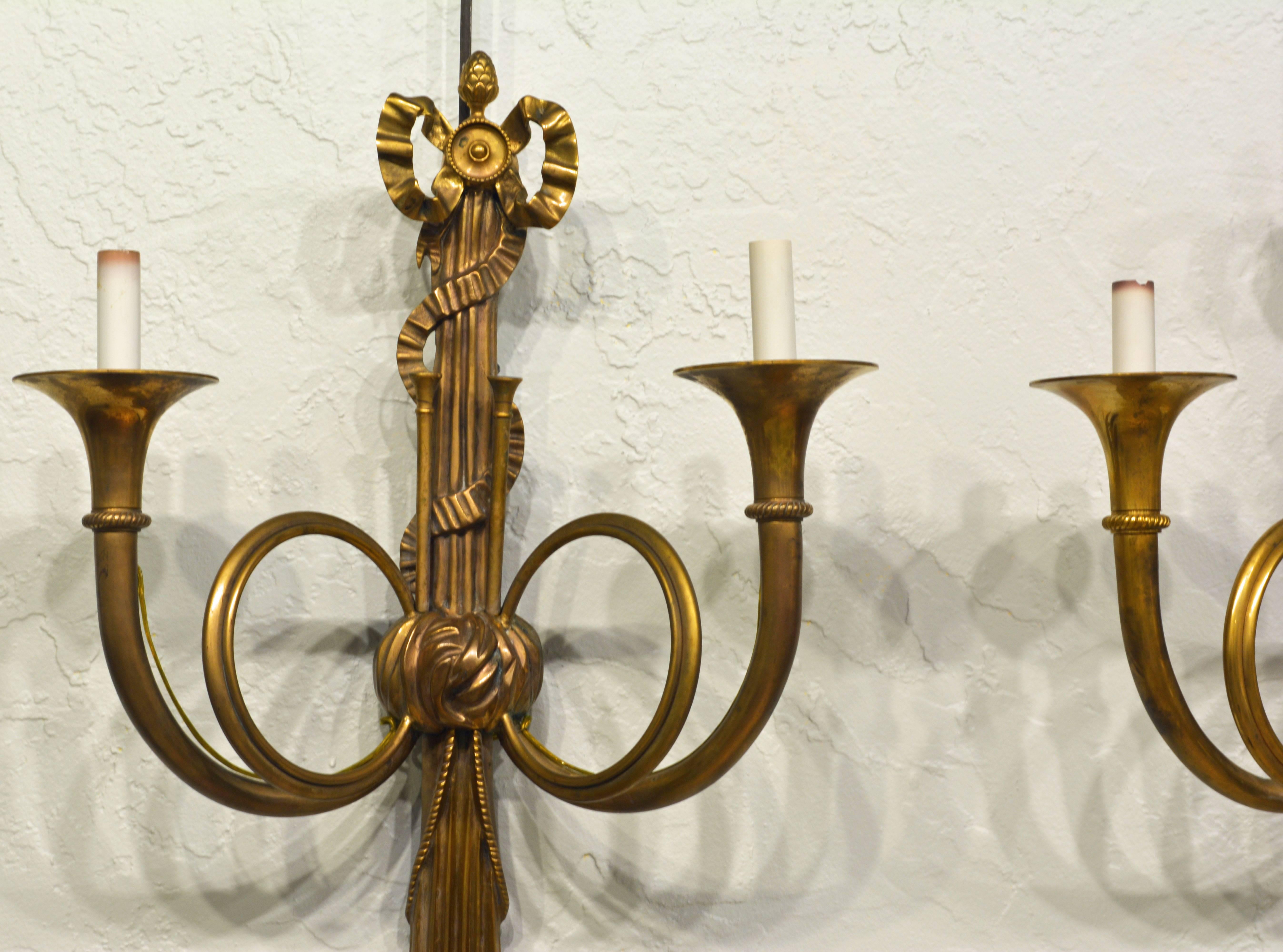 31 inches tall these wall sconces are impressively beautiful featuring each two light arms in the shape of hunting horns, topped by ribbon bow and ending in drapings with tassels, all in the Louis XVI tradition. The sconces are electrified.