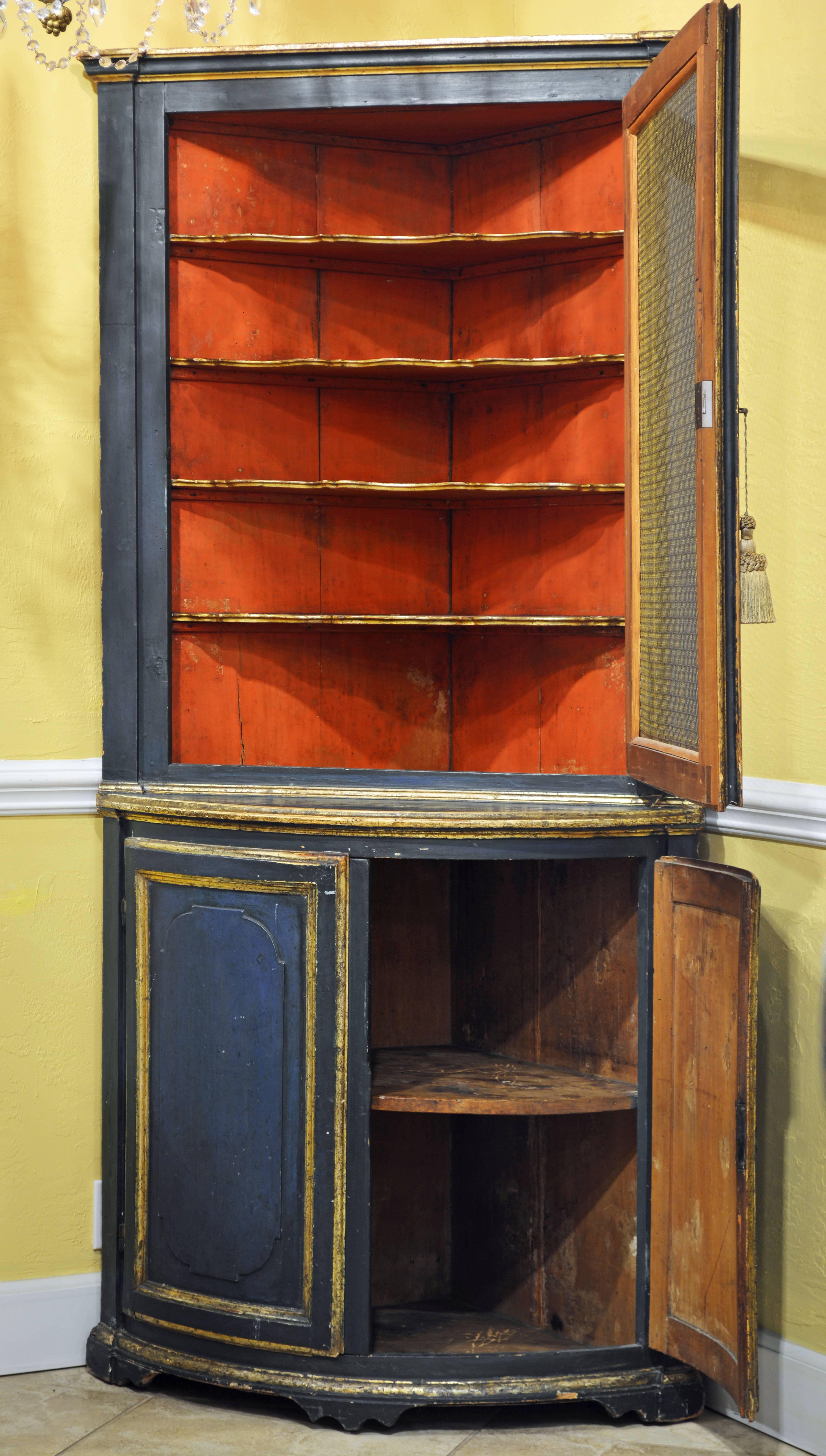 The combination of the subtle blue color and gilt trim makes this corner cabinet especially attractive. The two upper mesh doors open up to a Venetian red interior with shaped gilt trimmed shelves, the lower carved panel doors encloses a one shelf