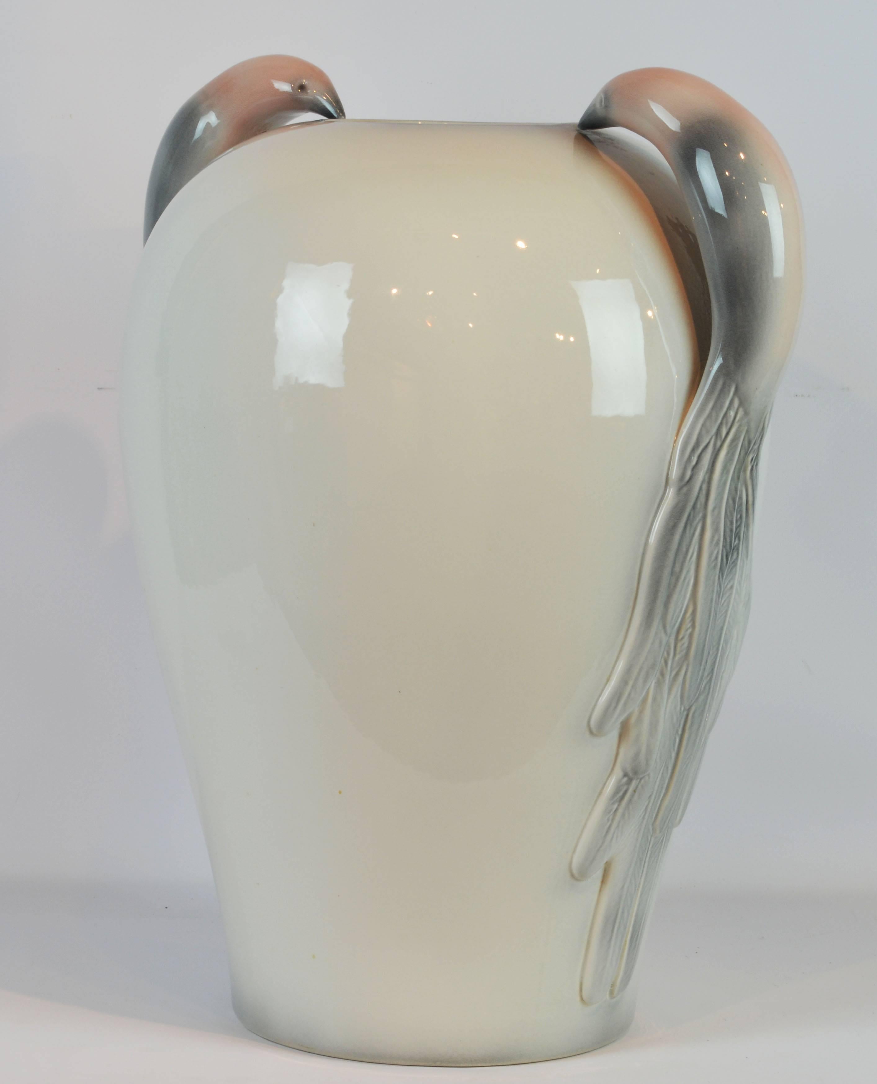 Standing 24 inches tall this elegant and unique vase of subtle color features a stunning pair of handles in the shape of birds of paradise stylized in the Art Deco manner.