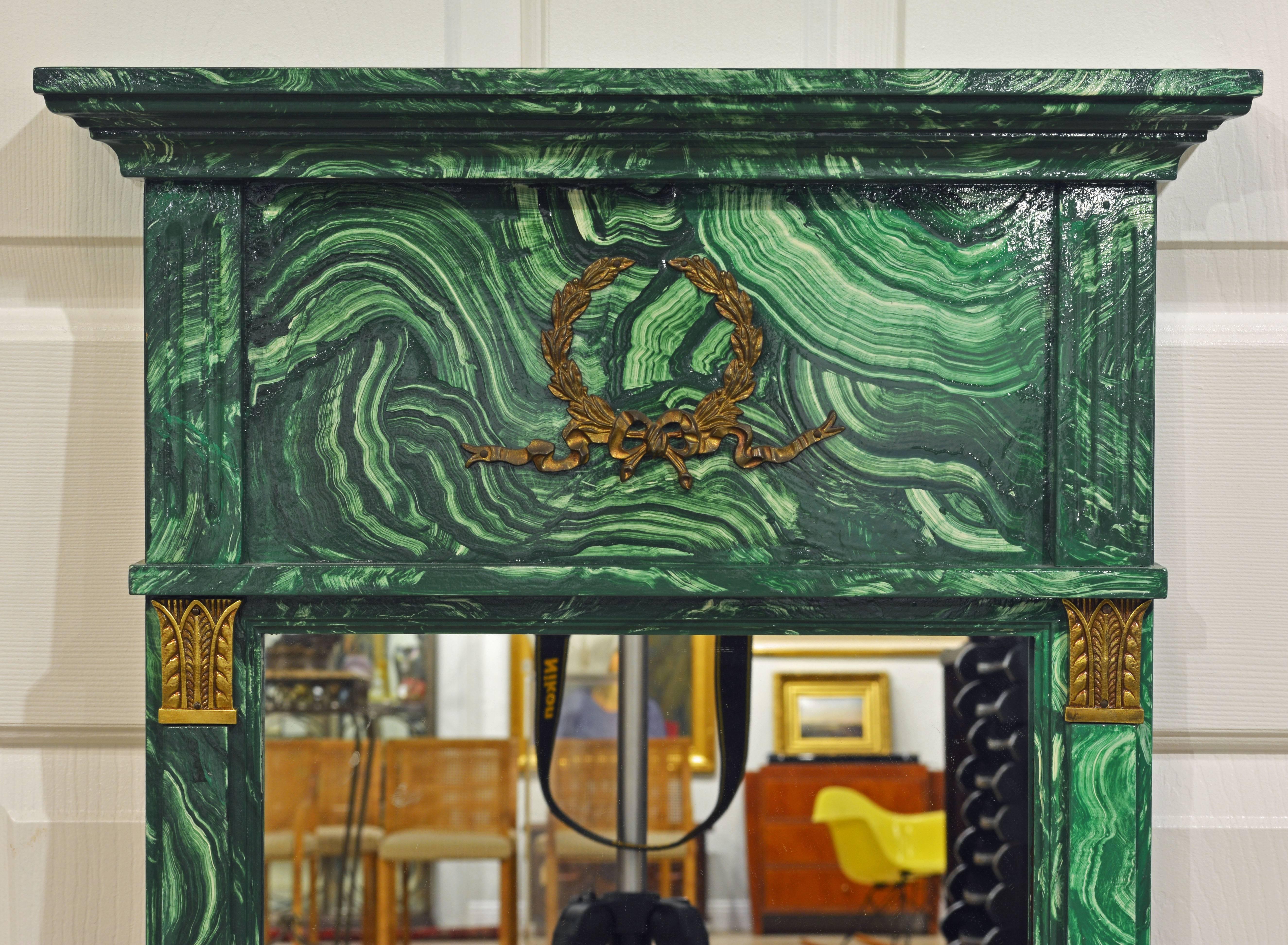 This malachite painted mirror features a neoclassical form with a moulded corniche and gilt bronze mounted top panel above the mirror flanked by bronze crowned pilasters.