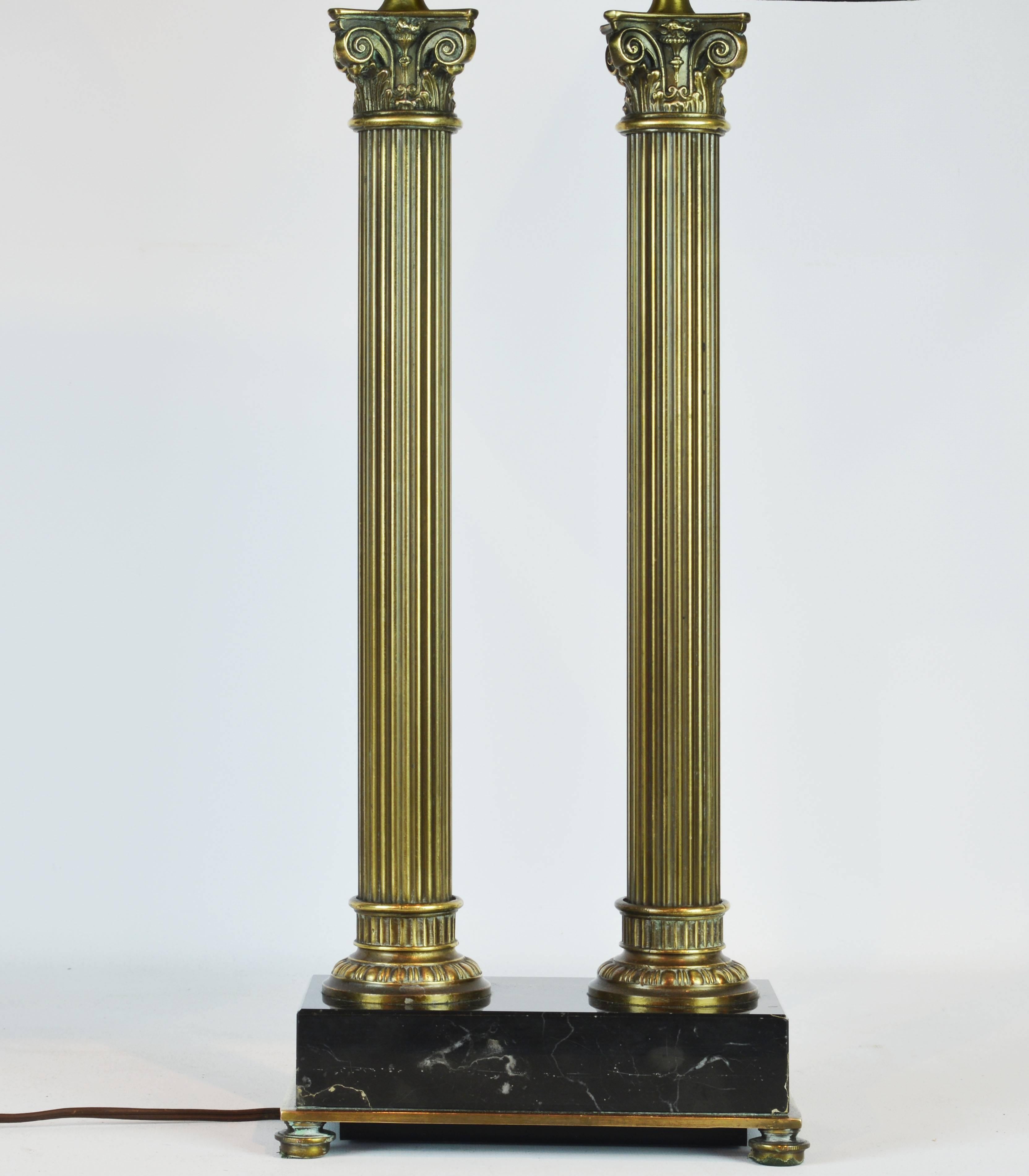 This French table lamp in the neoclassical architectural style features a bronze edged marquina marble base raised on bronze feet supporting two bronze columns surmounted by well detailed corinthian capitals. Measurements below are including the