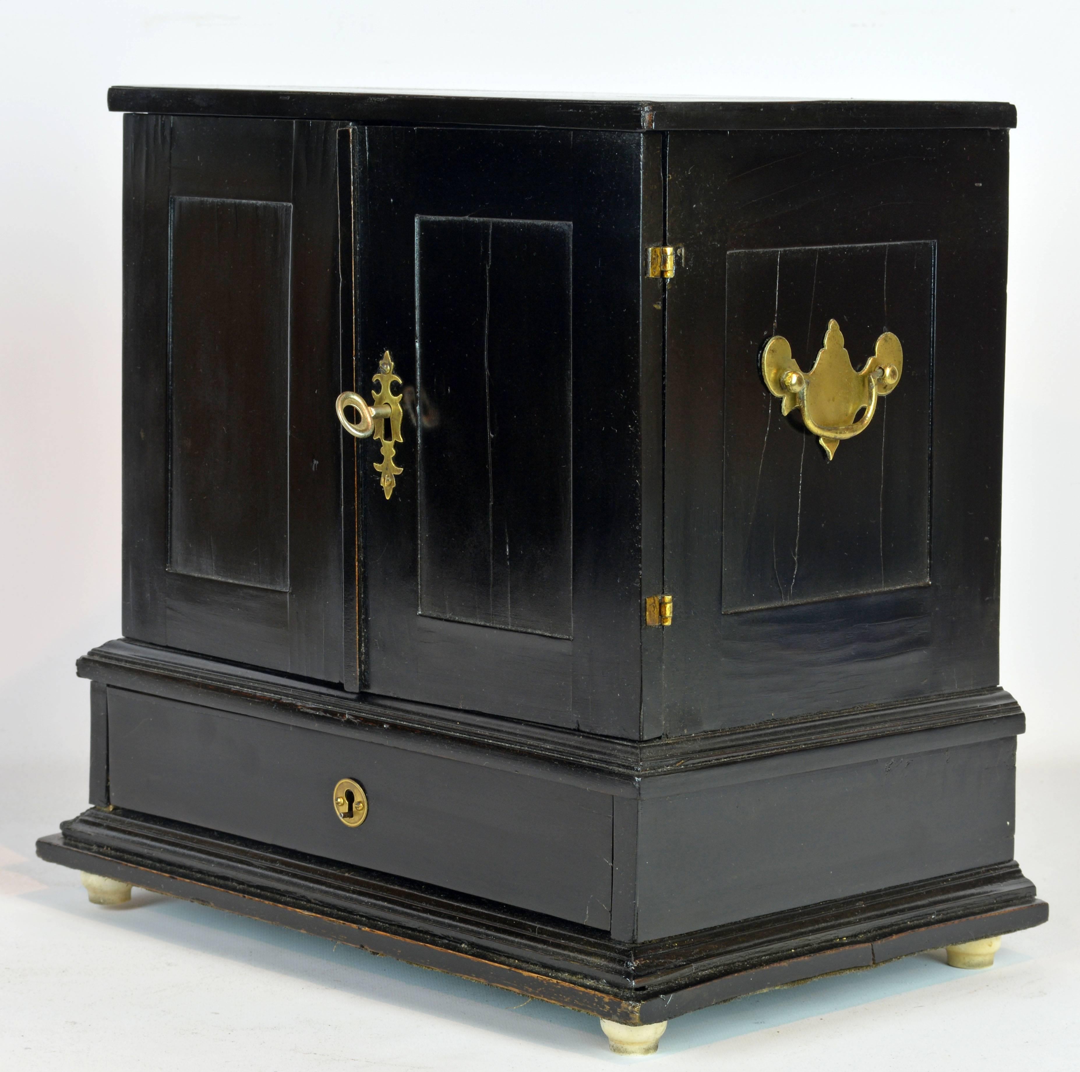 This fine cabinet fashioned in the North Italian tradition features two doors opening up to an interior fitted with small drawers above a long base drawer on a moulded base and raised on turned ivory feet. All drawers are inlaid with gracefully