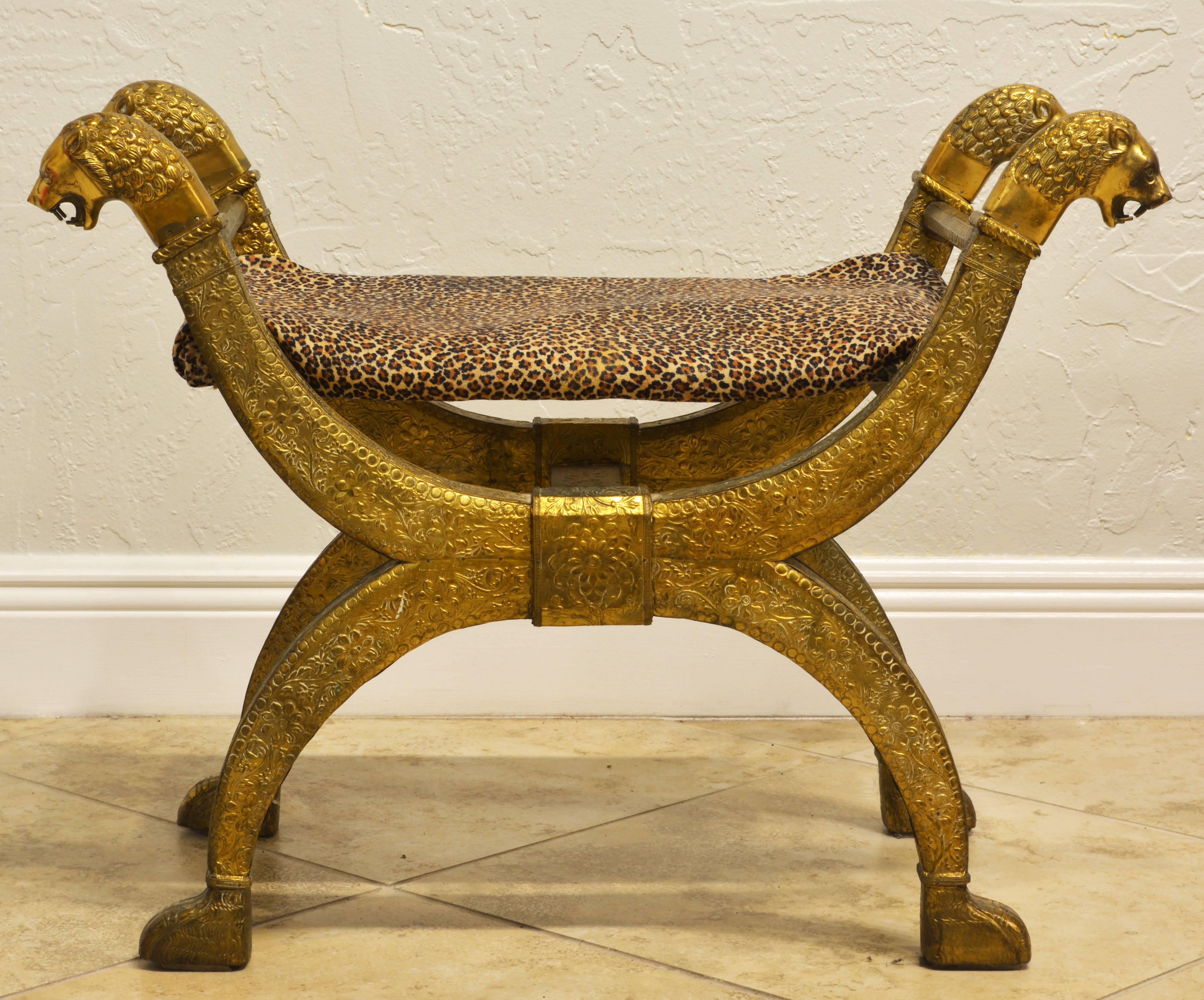 This exotic and beautifully detailed bench from the 1960s features the classical curule form adorned by four lion's heads and resting on paw shaped feet.