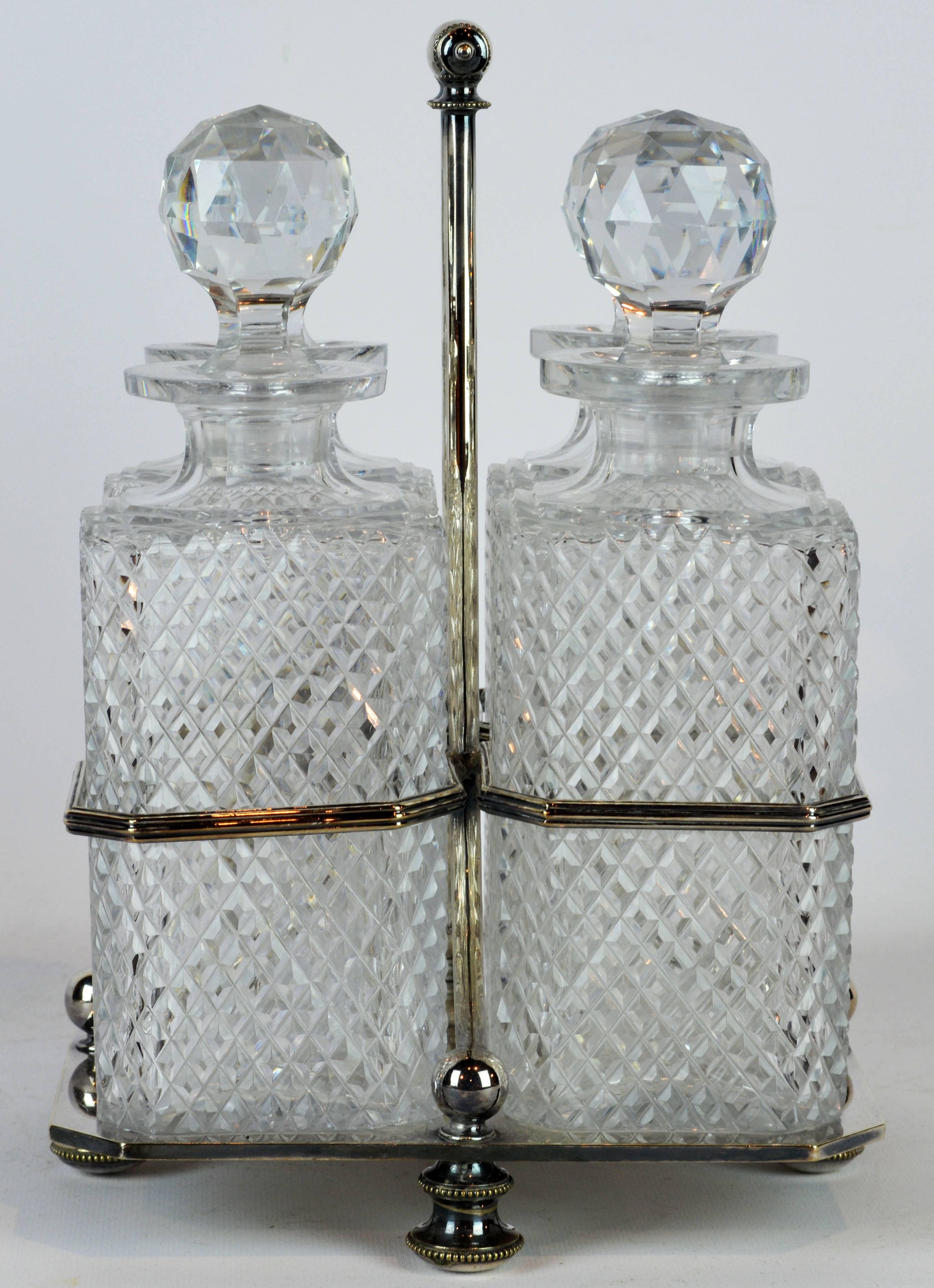 Of distinguished Georgian design this Tantalus decanter set features four cut crystal decanters with globe stoppers placed in a Sheffield silver plate carrying frame with elegantly fashioned top handle. It is marked on the bottom as shown on photos.