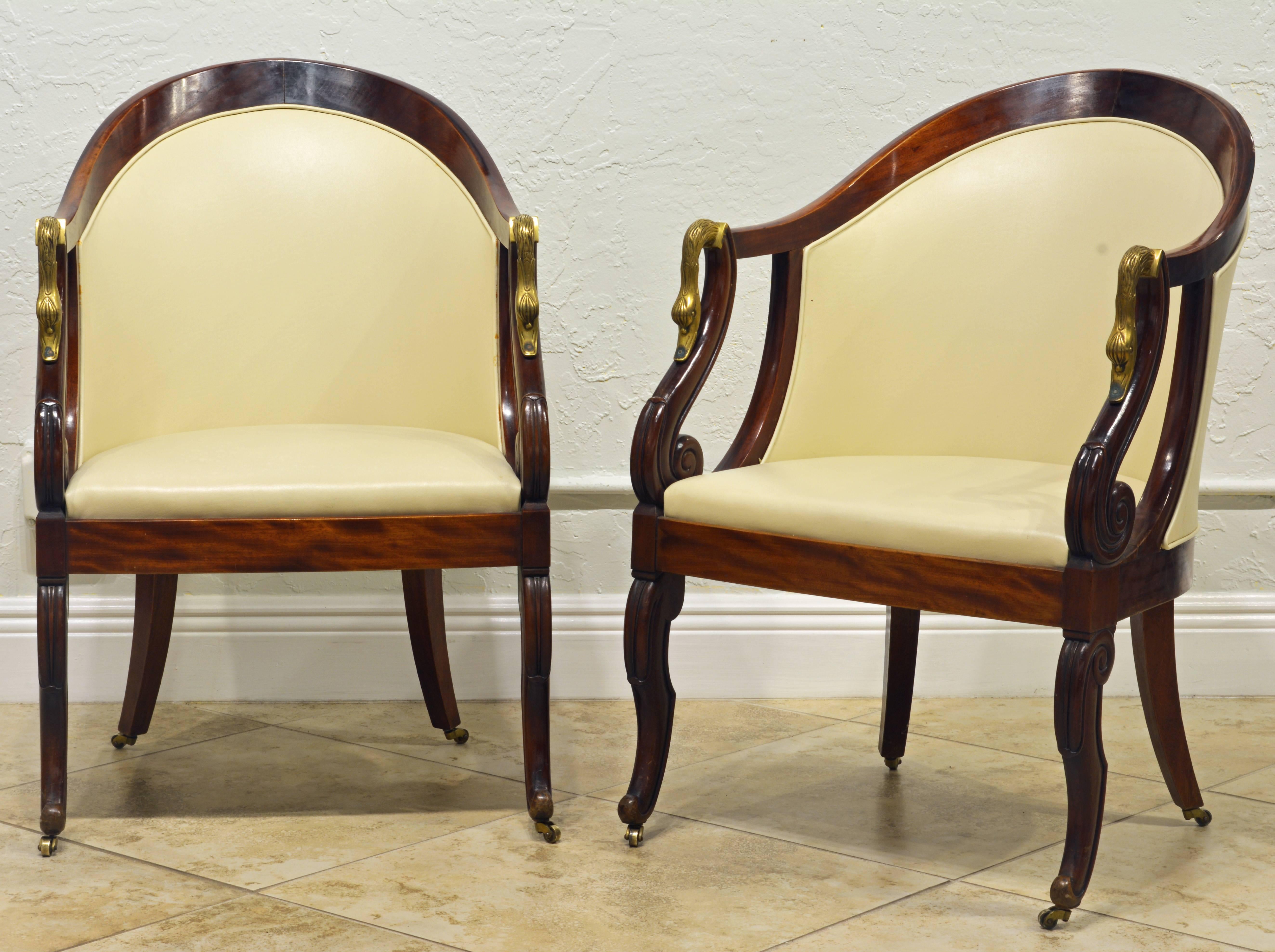 These chairs from the second half of the 19th century feature elegant curved backs and beautiful open arm rests accented by brass swan figures. The carved and scrolled front legs as well as the classical saber back legs rest on small brass castors.