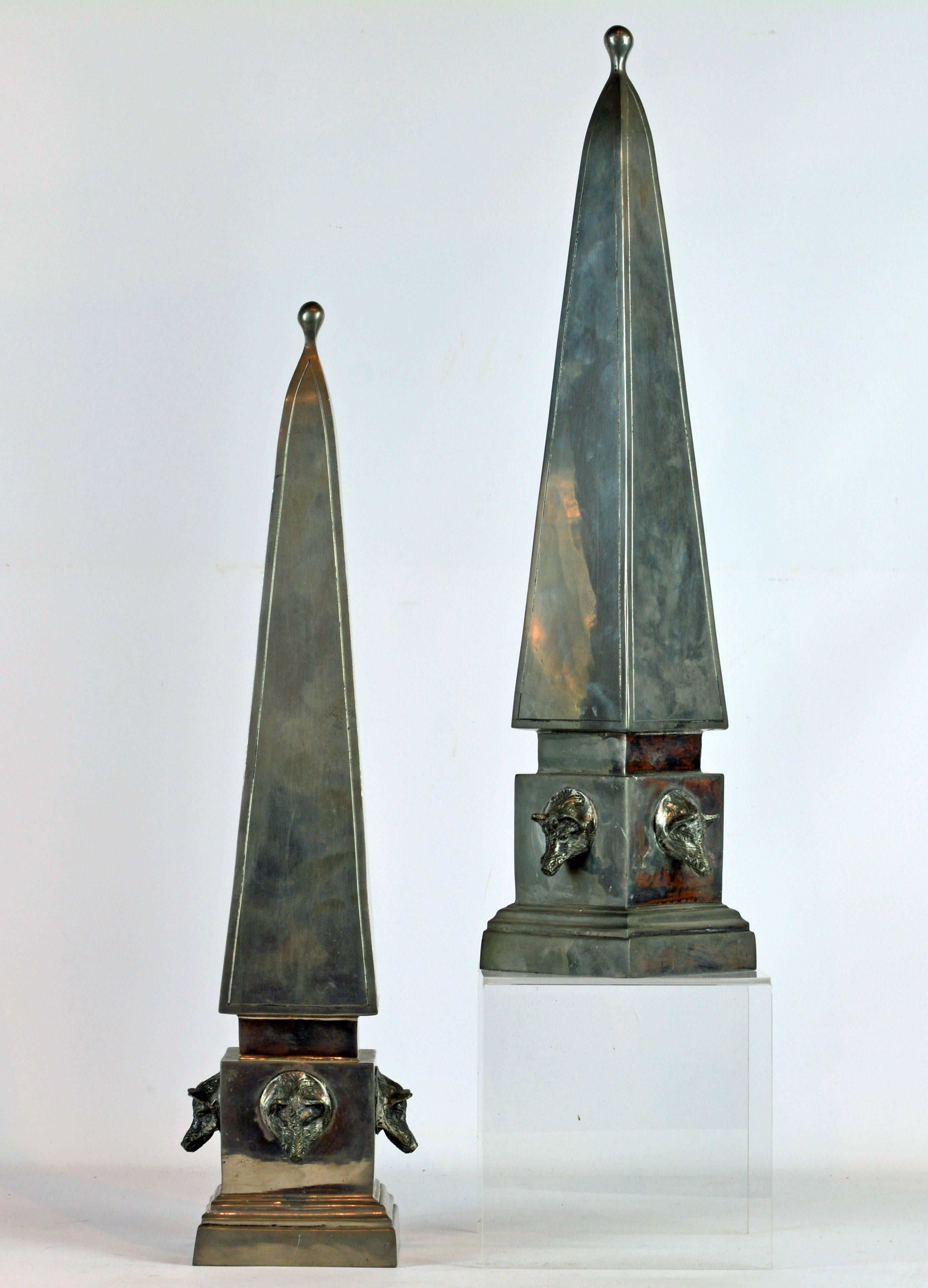 Standing 20 inches tall these unique hunting themed pewter obelisks model in the neoclassical style feature beautiful craftsmanship and detail. Each base is mounted with four boar's heads adding a sculptural quality to their appearance. The obelisks
