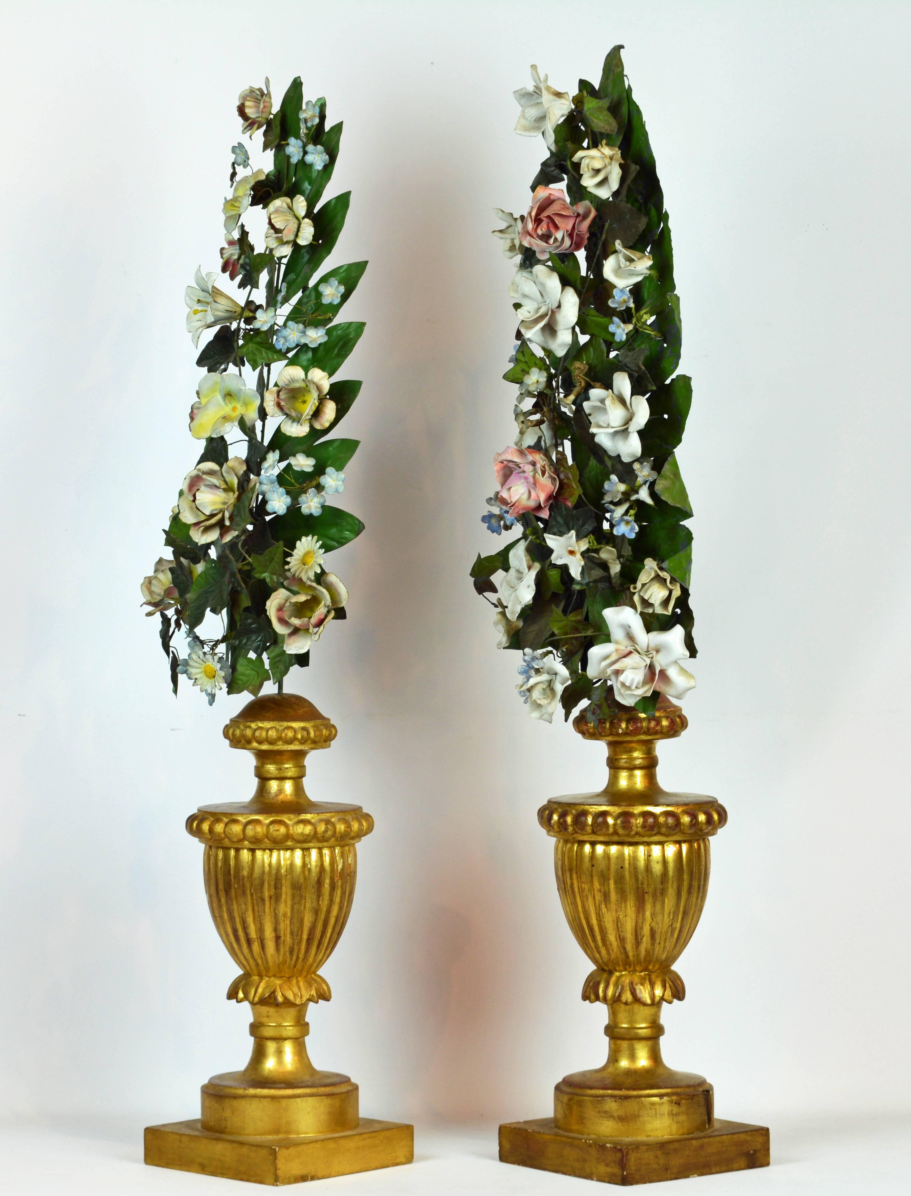A lovely pair of table decorations with hand carved gilt wood urns supporting tall arrangements of polychrome painted tole flowers and leaves. A closer look at the photos shows the multitude of different flowers combined. 19th Century