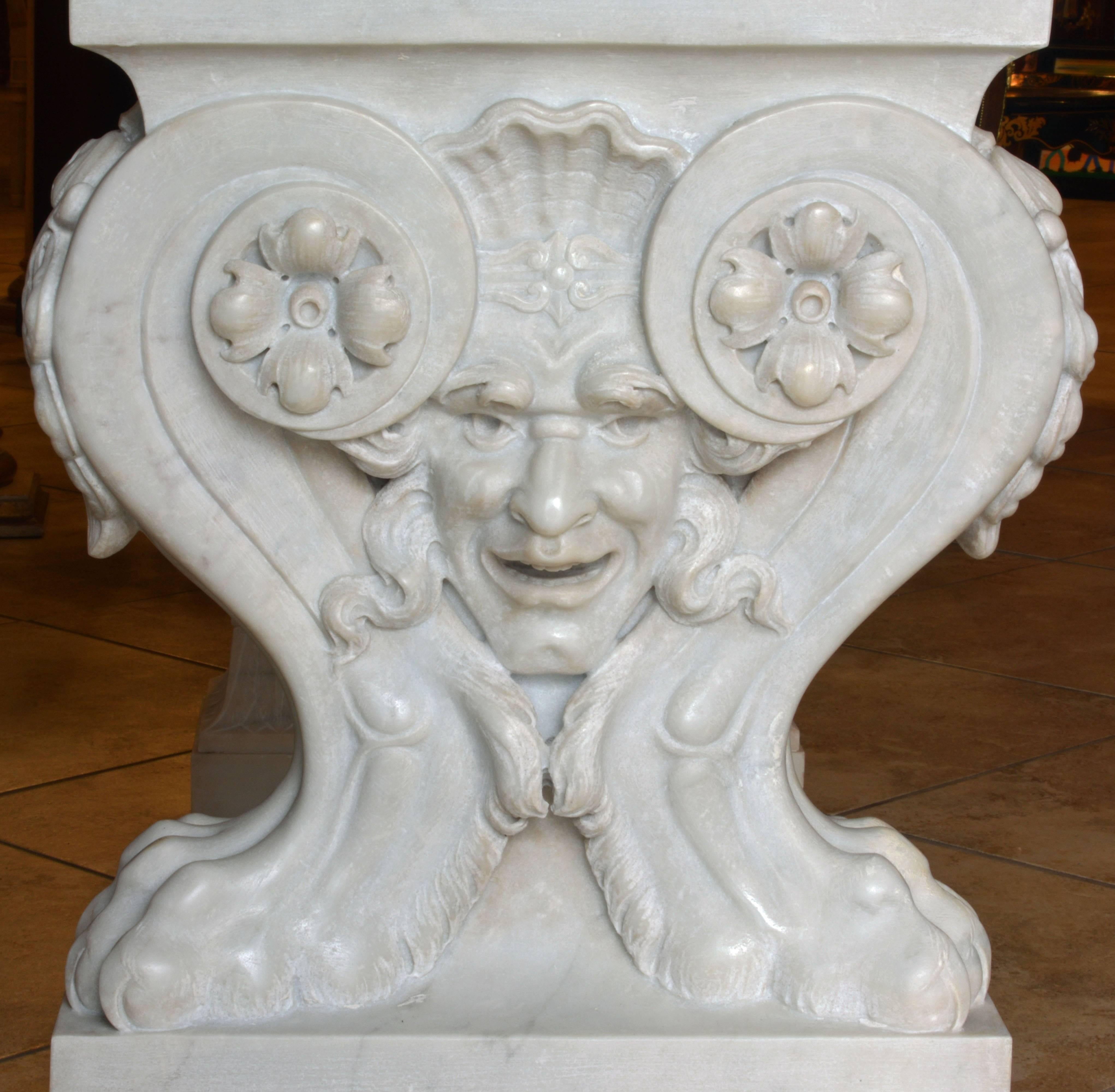 A piece of sculptural art itself this table features a white Carrara marble-top, centering a circular classical bas-relief, with leaf carved edges above two magnificent pedestals carved with pairs of lion legs resting on square leaf carved bases and
