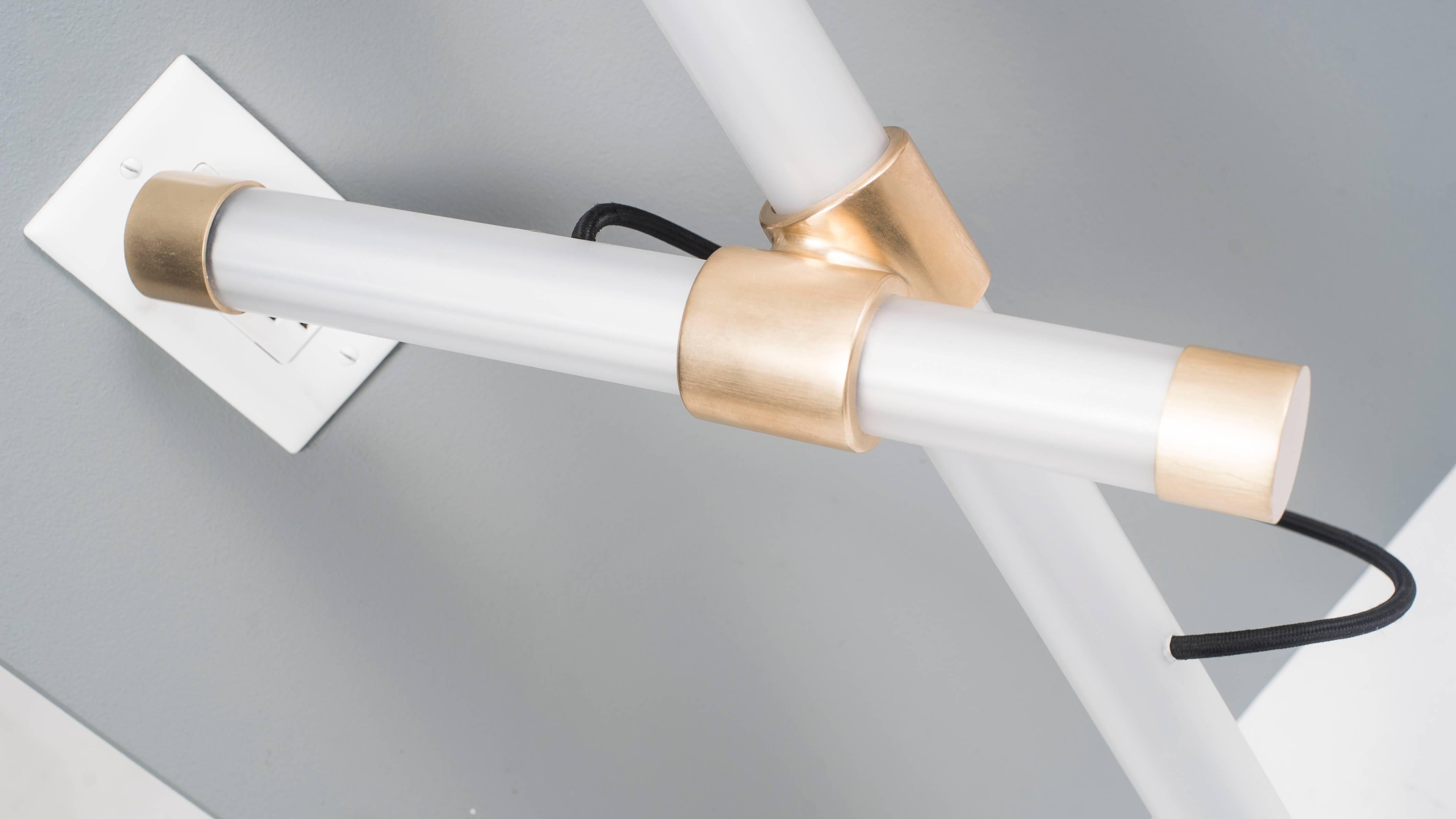 The Leaning Axis Light is a modular lighting fixture that plugs directly into a wall. The brushed brass connector holds each dimmable LED bulb in place while the handmade end caps keep the piece visually balanced. One can rotate the bulbs to adjust