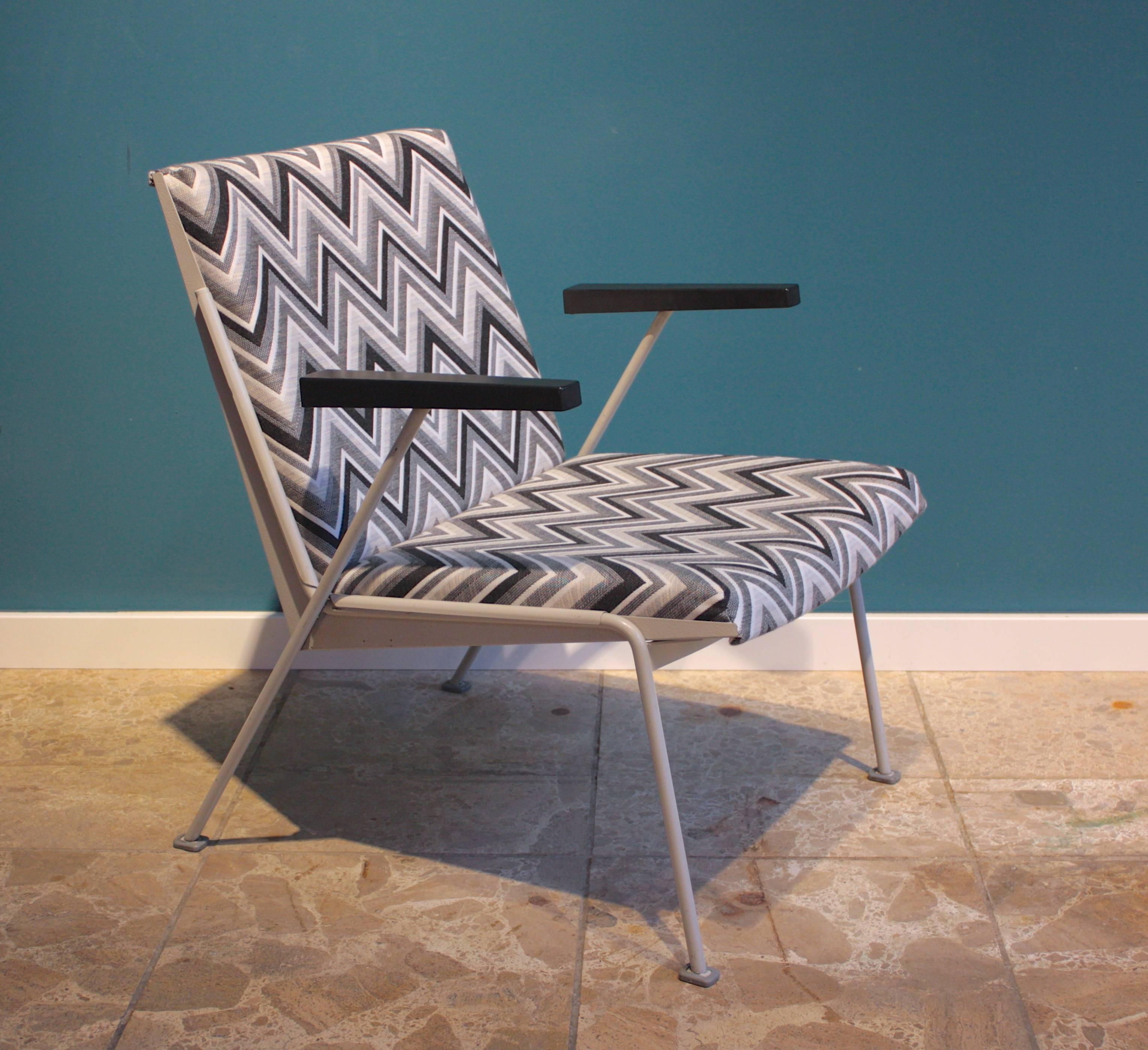 The Oase chair was designed by Wim Rietveld for Ahrend de Cirkel in 1958. The frame structure is made of grey lacquered steel, the armrests are made of bakelite. The chair is newly upholstered with graphic black and white zig zag patterned fabric.