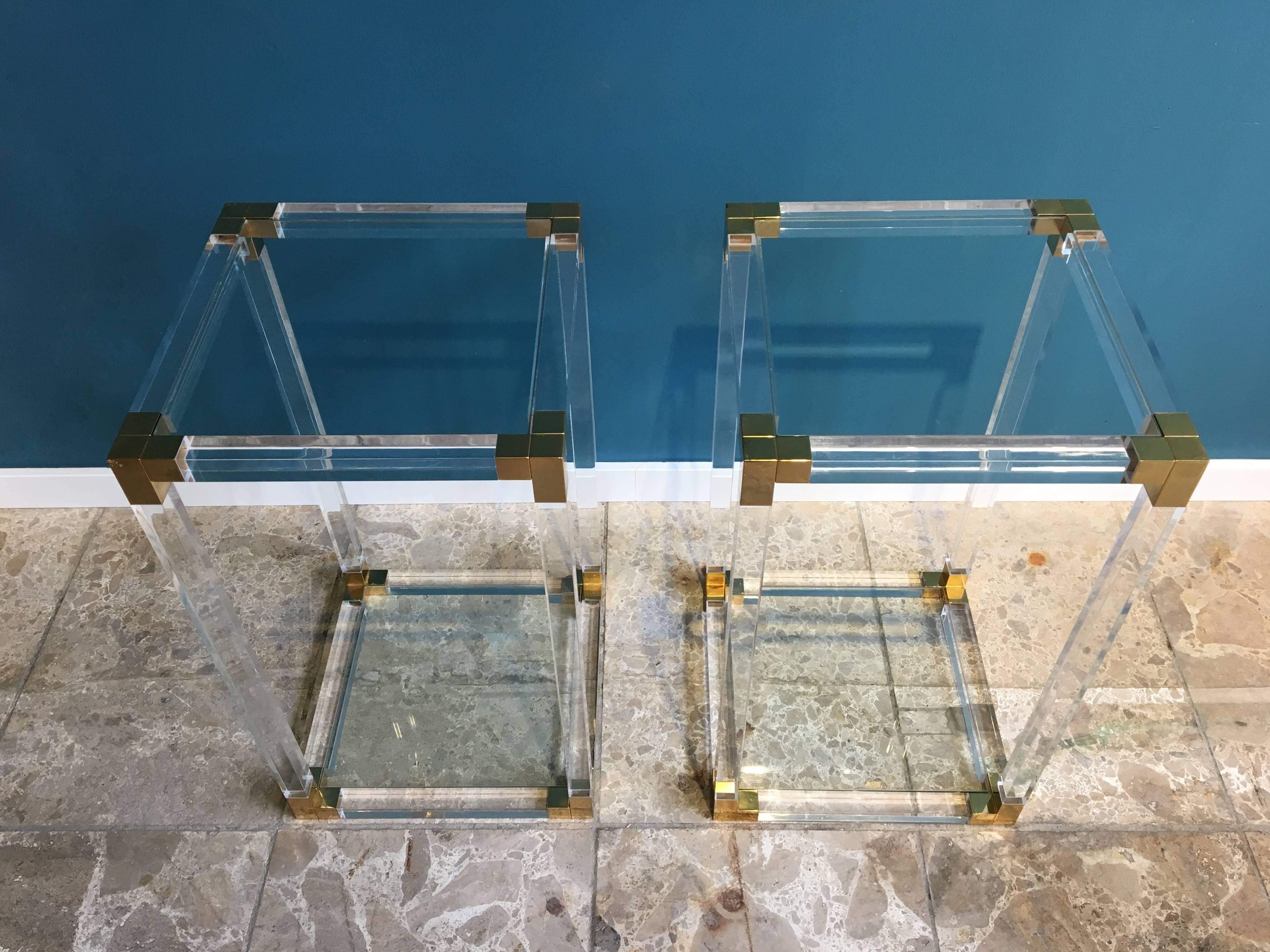 Glamorous pair of acrylic and brass side tables with a glass tops and bottoms. The acrylic and glass are in good condition and the brass shows some age and oxidations.