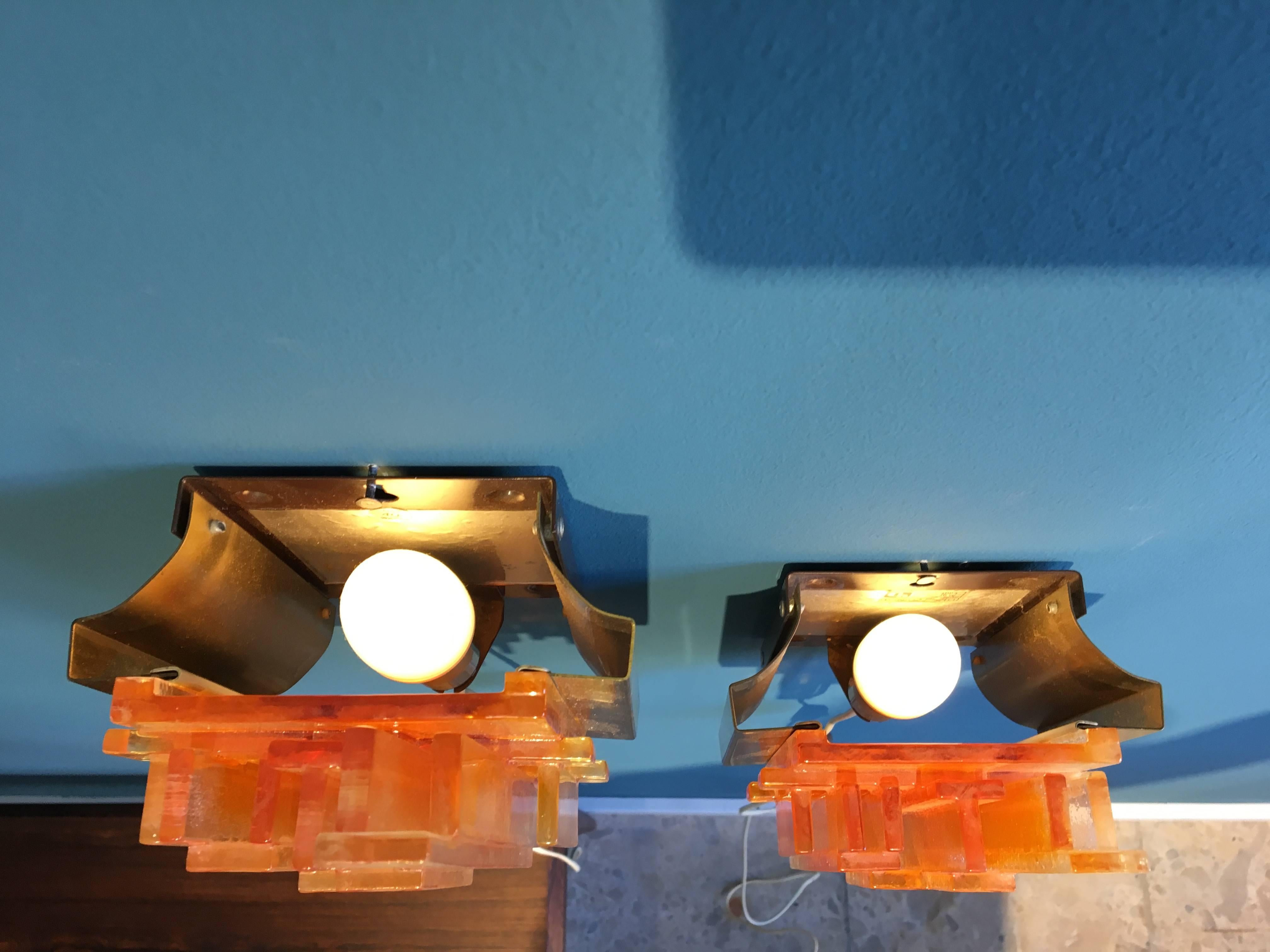 This set of two wall lamps called Model 1004 was designed by Claus Bolby and produced by Danish company Cebo Industri in the 1970s. The lamps have a switch and still have their original stickers. The acrylic has colors of orange, yellow and white