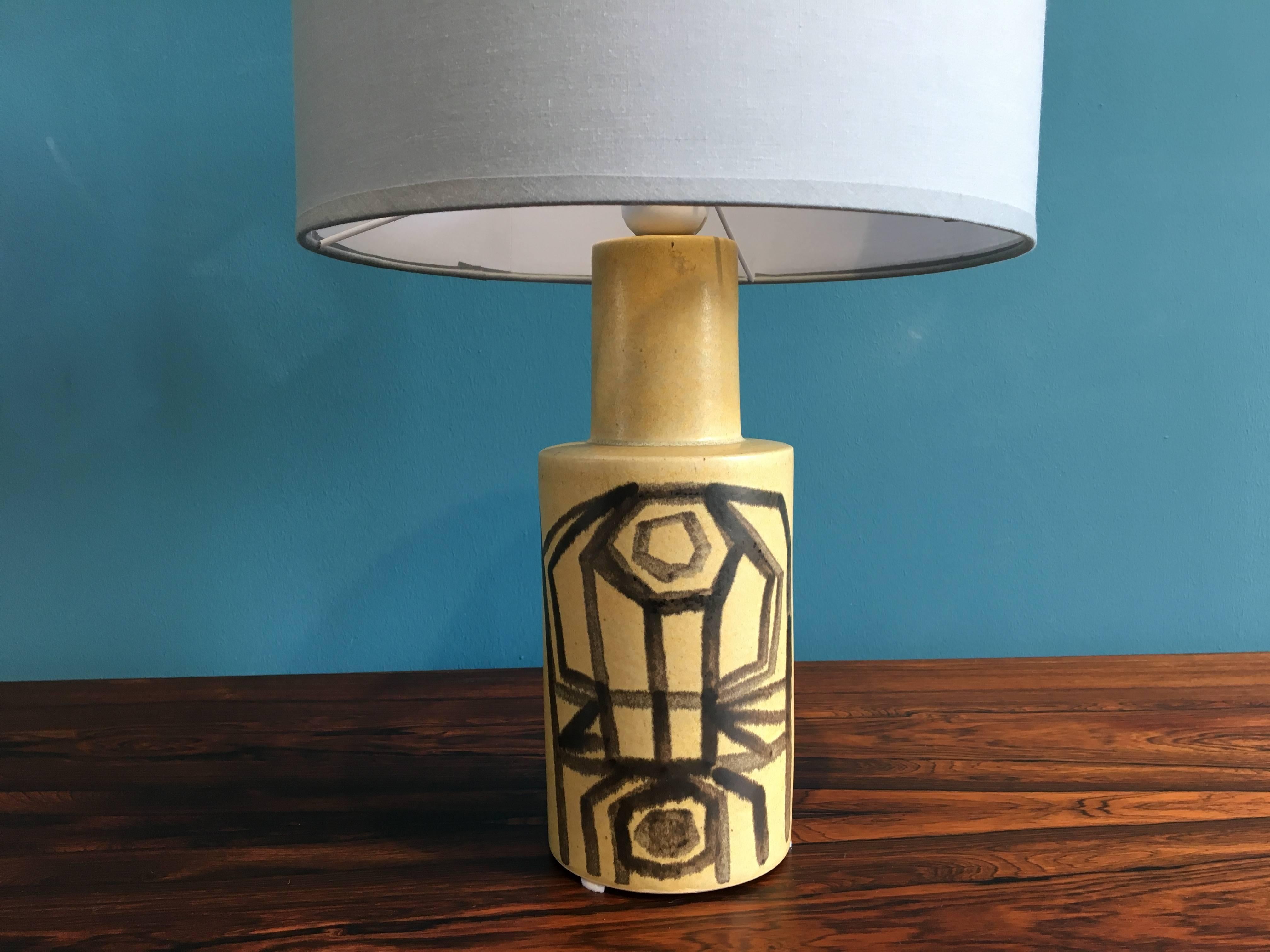 This table lamp was produced by Danish company Okela in the 1970s. It is made of ceramic and features a graphic pattern on the front. The lamp has been rewired with a switch and has a new socket and shade.