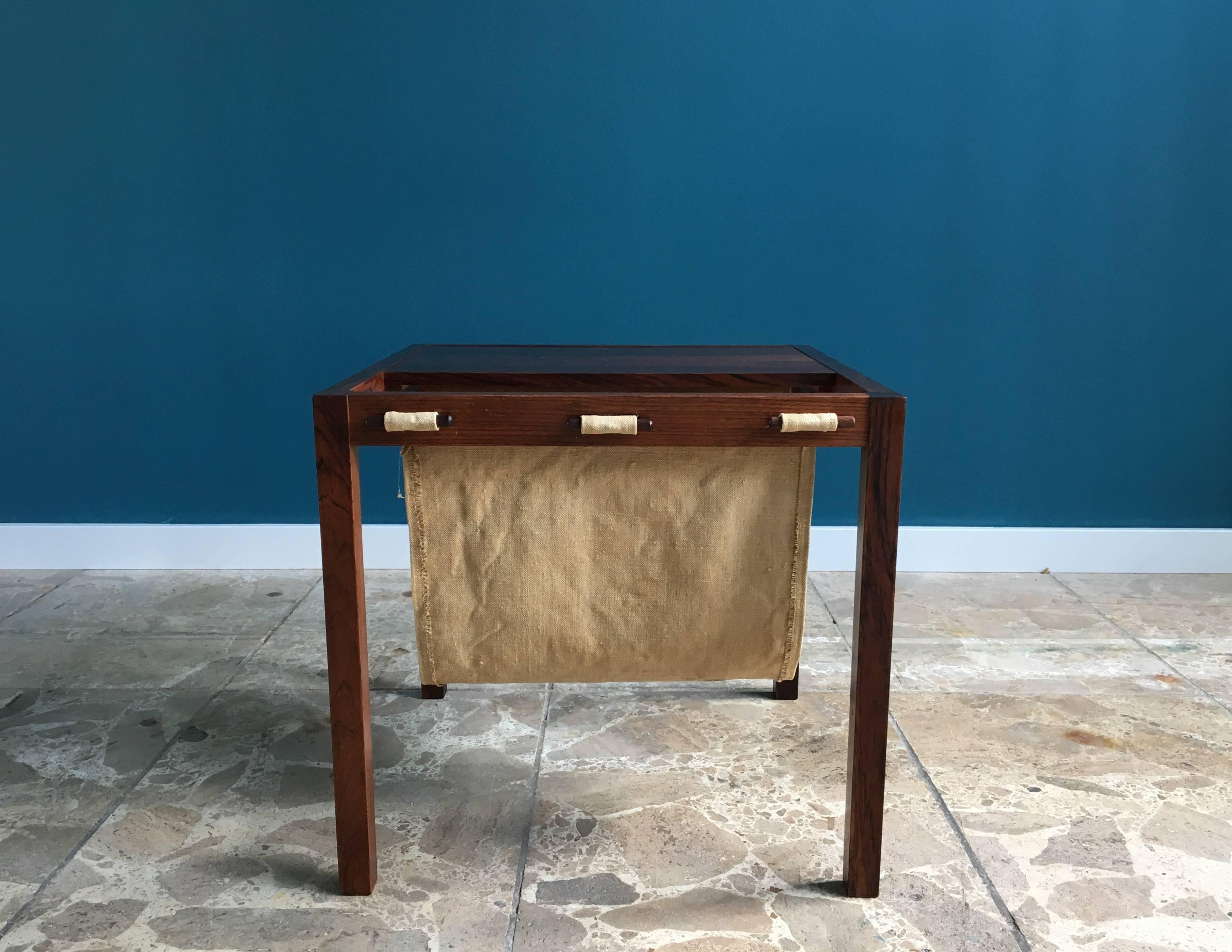 This square side table was made in Denmark in the 1960s and is made of rosewood. Solid construction with canvas used in a sling form to hold magazines and other articles.